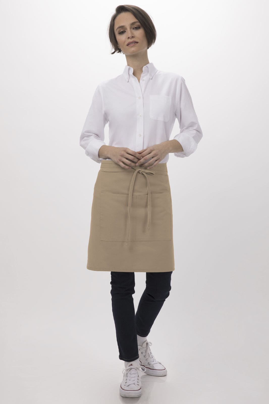 A person wearing a beige half bistro apron over a white shirt and black jeans, with a logo visible on the apron.