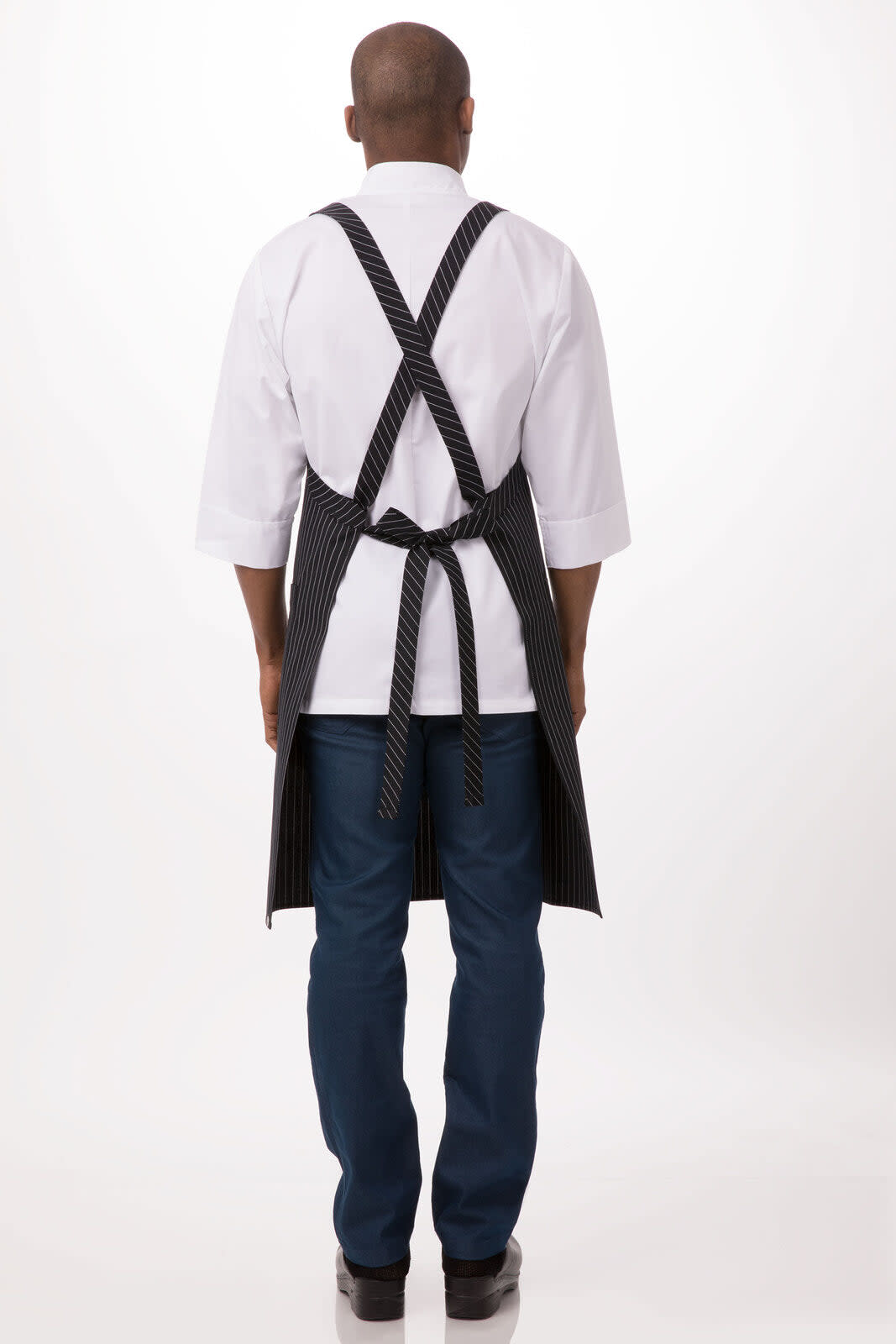 A black and white striped cross-back bib apron worn by a person standing with their back to the camera.