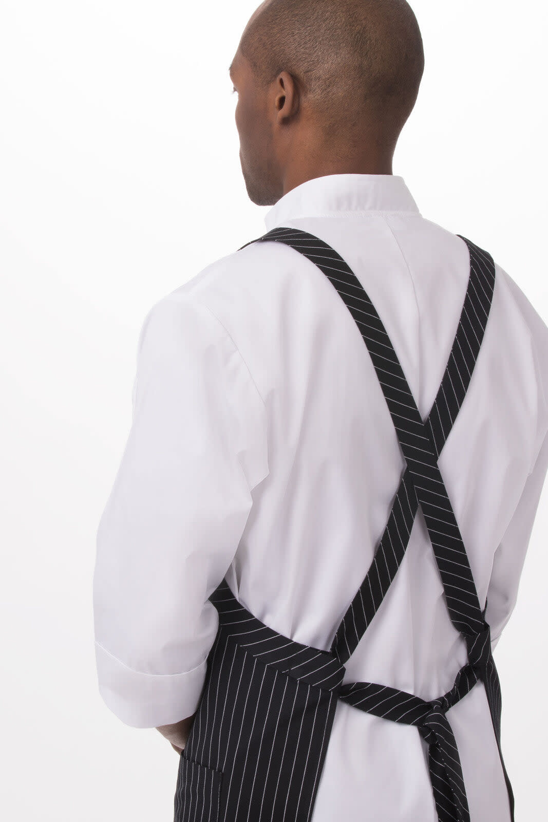 A black and white striped cross-back bib apron is worn over a white shirt, featuring adjustable straps at the back.
