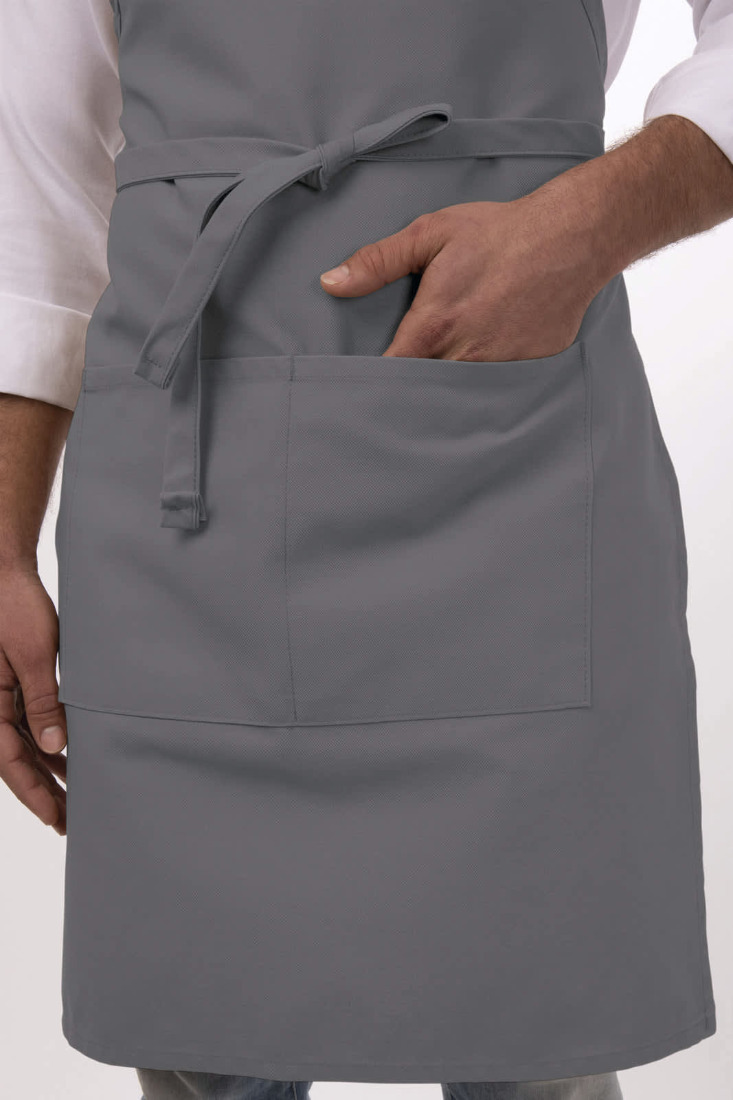 A grey bib apron with a front pocket, worn by a person with one hand inside the pocket.