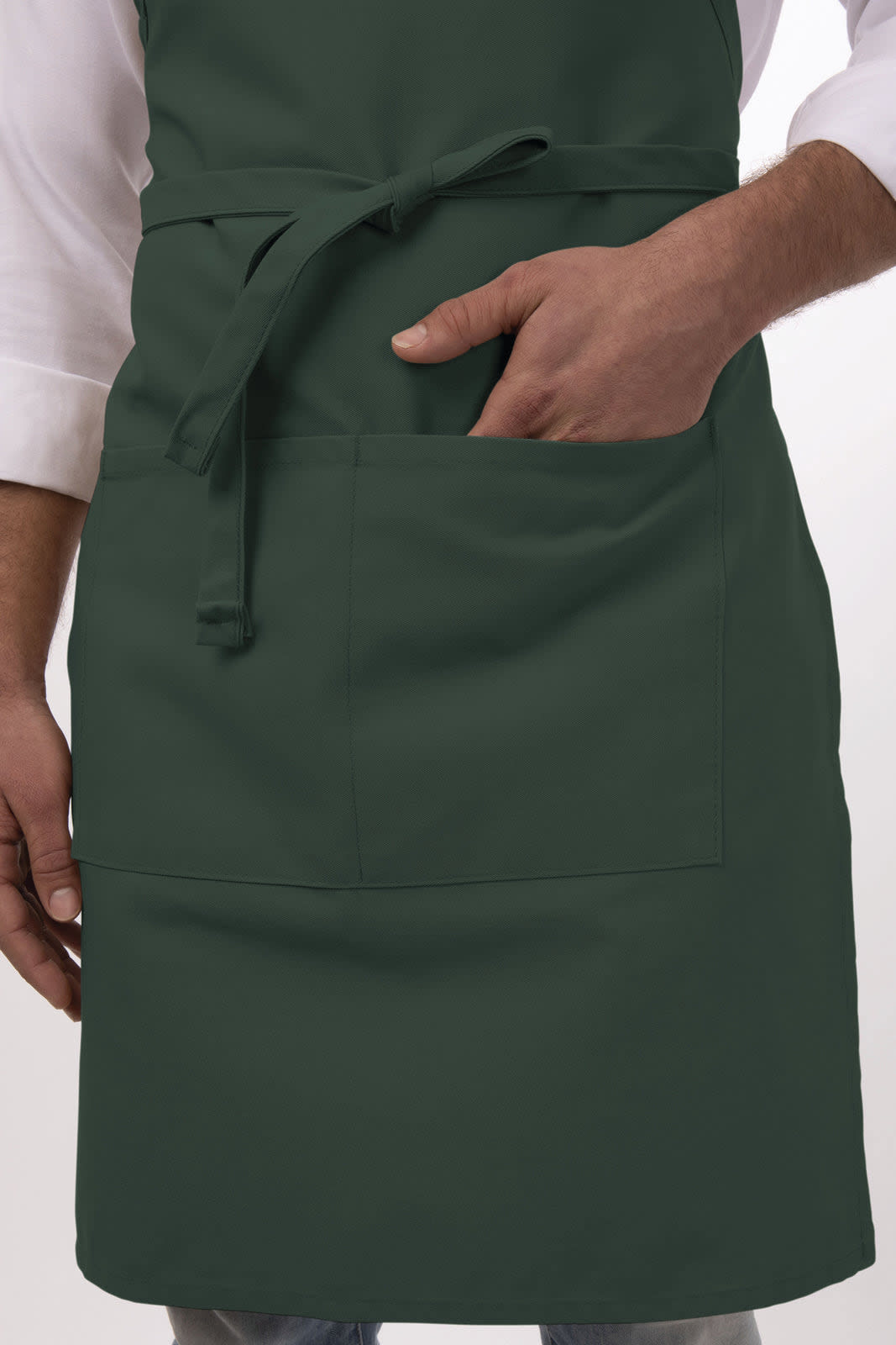 A dark green bib apron with a front pocket, worn by a person holding their hand in the pocket.