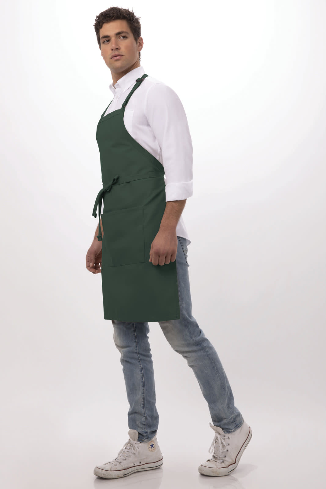 A green bib apron on a model, featuring a tie at the waist and adjustable straps, paired with a white shirt and jeans.
