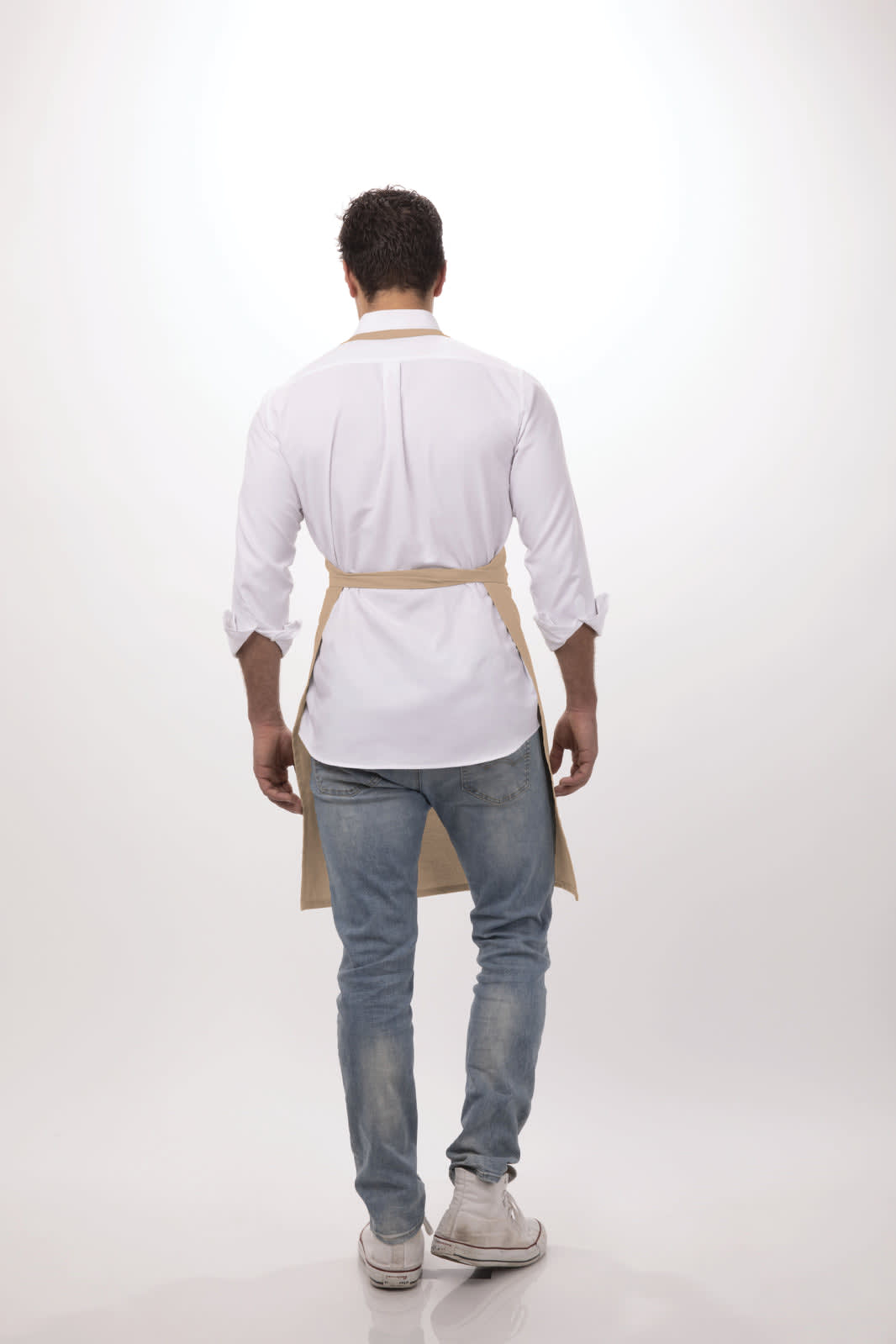 A person wearing a beige bib apron over a white shirt and jeans, facing away from the camera.