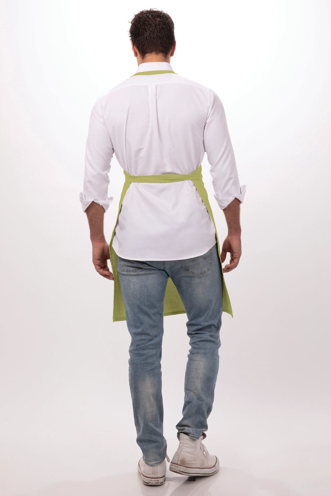 A man wearing a white shirt and blue jeans, with a green bib apron tied at the back. The apron has a logo.
