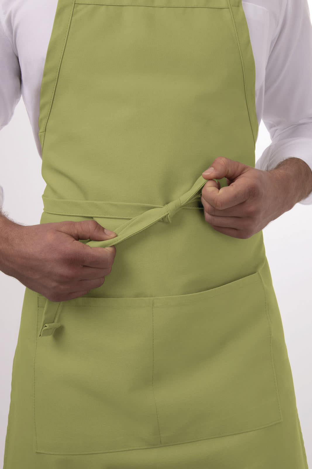 A green bib apron is being adjusted by a person. The apron features a front pocket and has a logo.