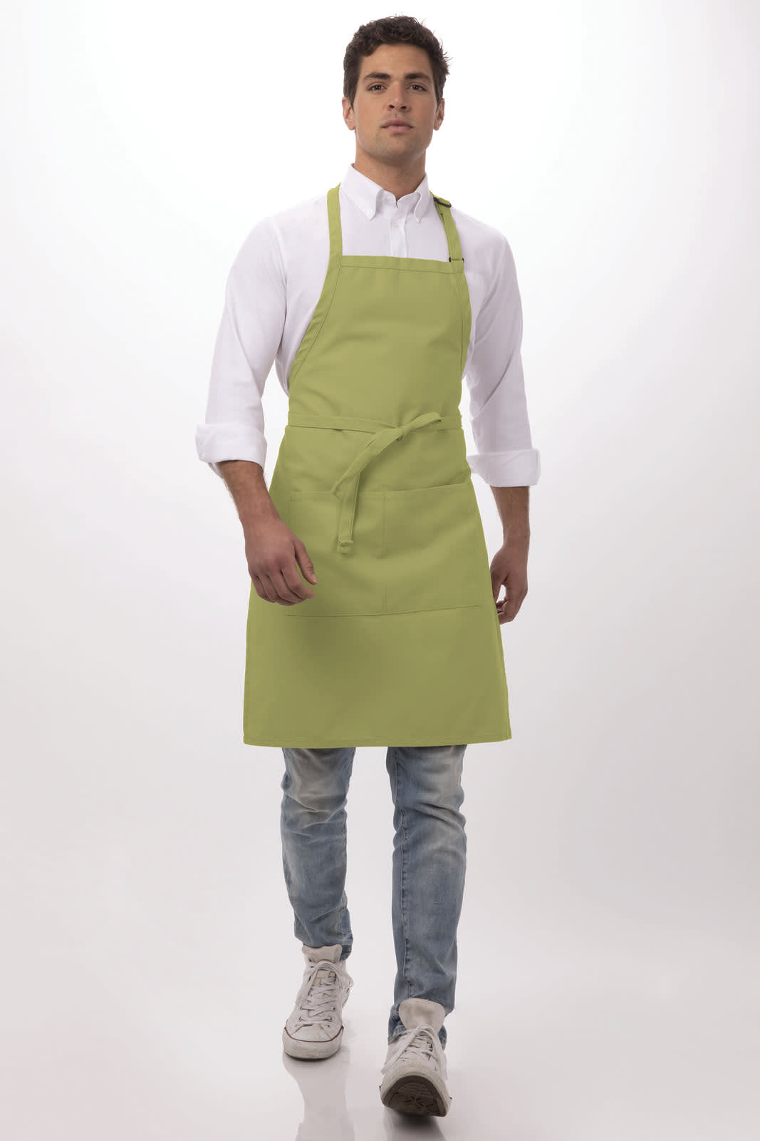 A man wears a light green bib apron over a white shirt and jeans, featuring a logo on the apron.