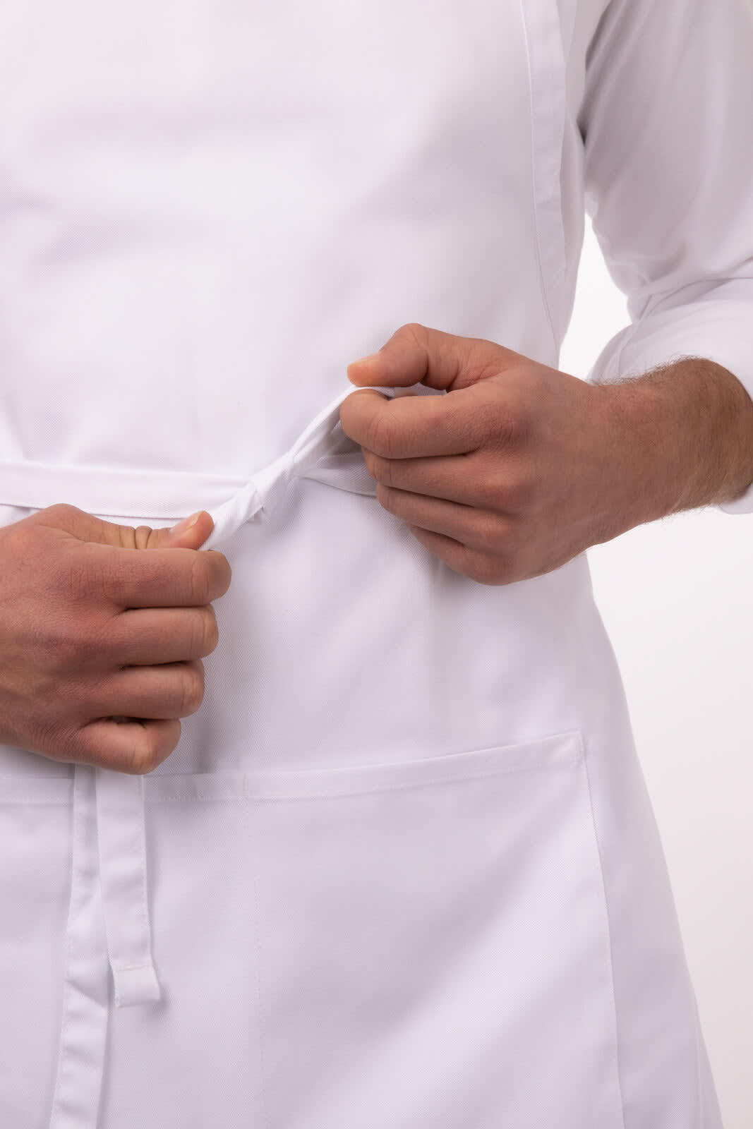 A white bib apron being adjusted at the waist with hands. The apron features a pocket and has a logo.