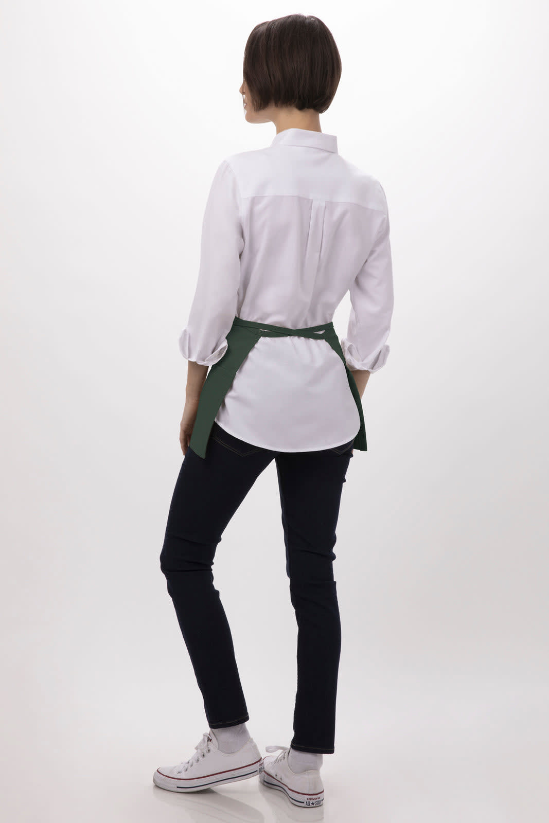 A person wearing a white shirt and dark jeans, with a green waist apron tied around the waist, shown from the back.