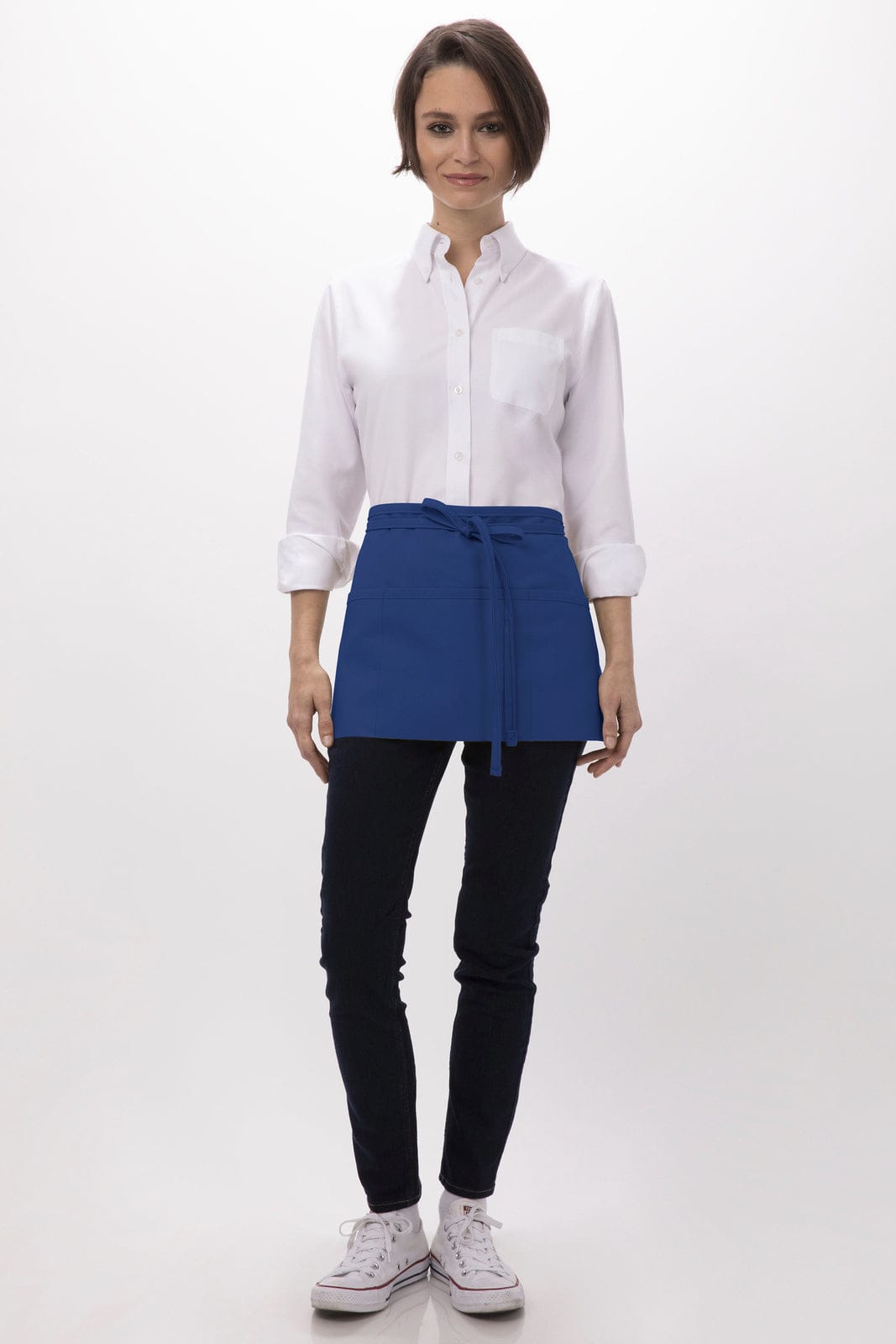 A waist apron in blue worn over a white shirt, paired with black pants and white shoes. The model stands front-facing.