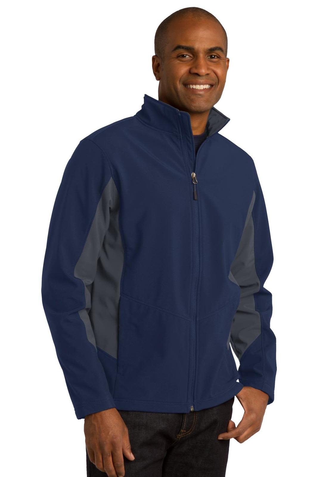 A man is wearing a navy blue soft shell jacket with grey accents and a zippered front. The jacket features a logo.