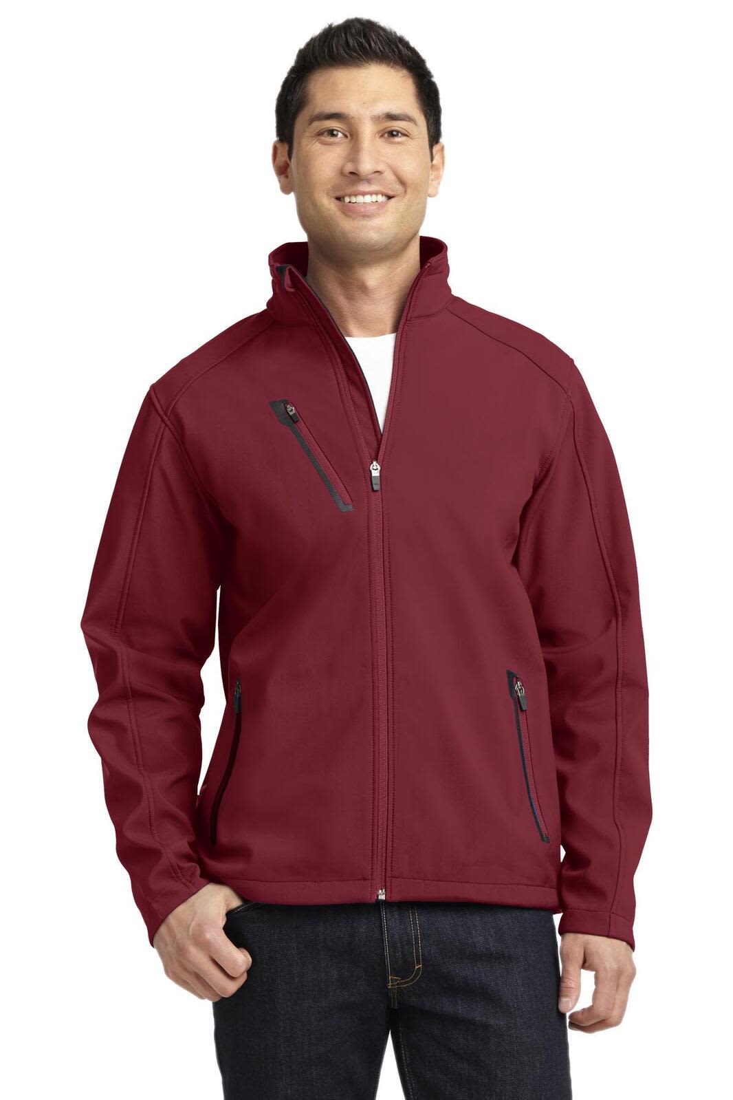 A man wearing a maroon Port Authority welded soft shell jacket with zippered pockets, featuring a logo.