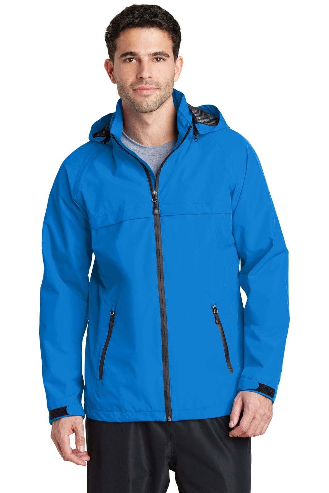 A man wearing a bright blue waterproof jacket with a hood and zipped pockets, featuring a logo on the chest.