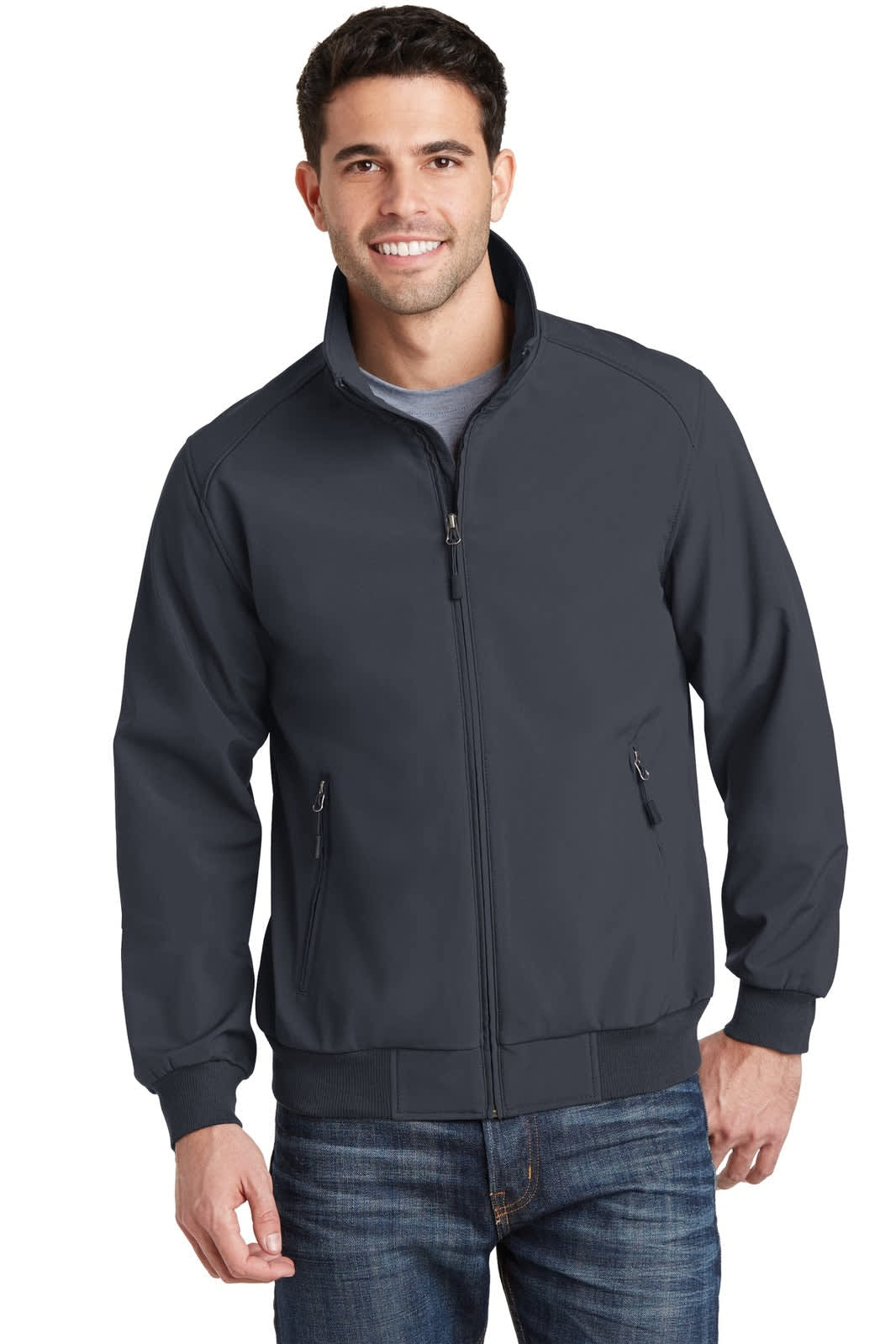 A man wearing a dark grey soft shell bomber jacket with a zip and side pockets, paired with blue jeans.