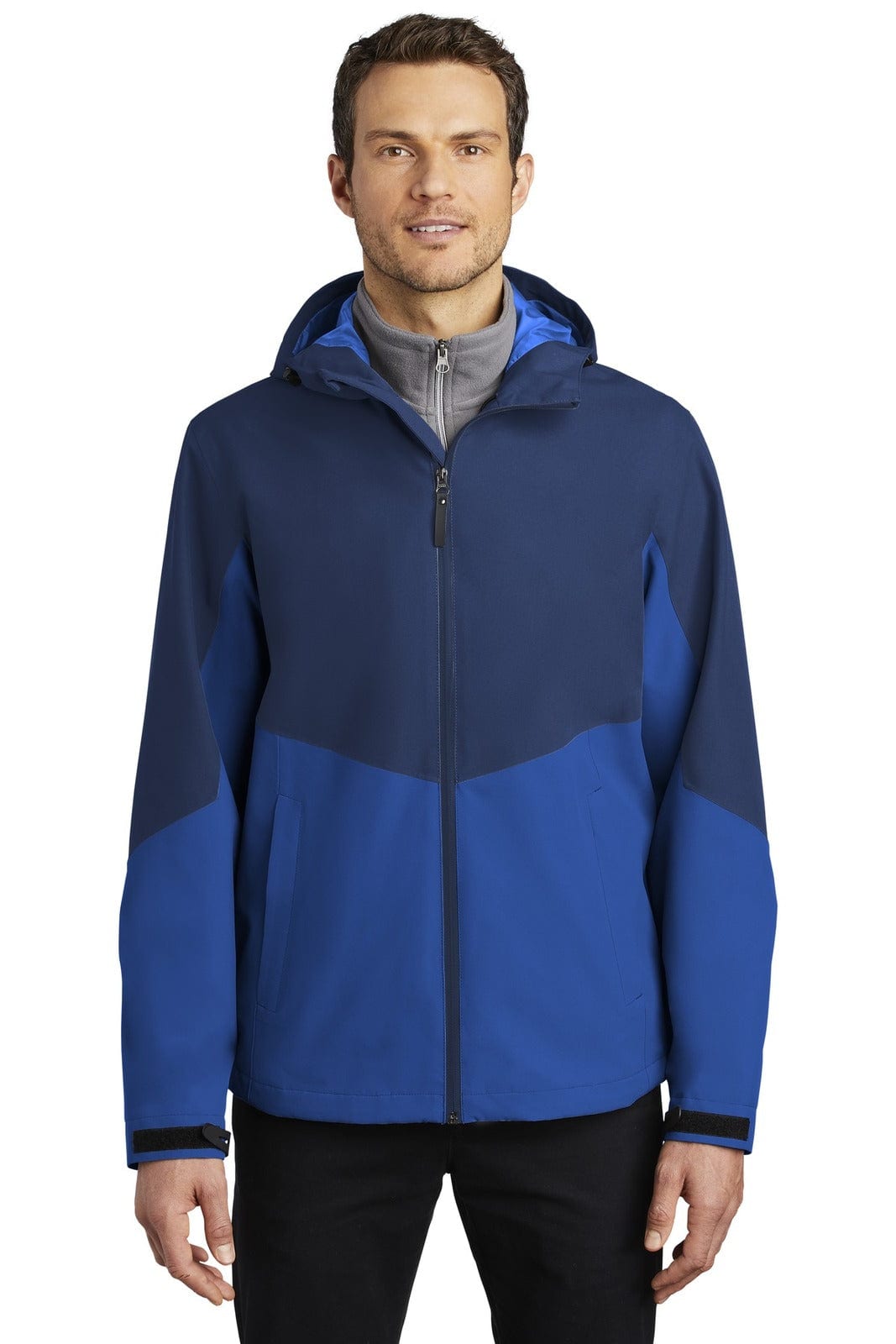 A blue rain jacket featuring a hood and contrasting panels, presented on a model. The jacket has a logo on it.