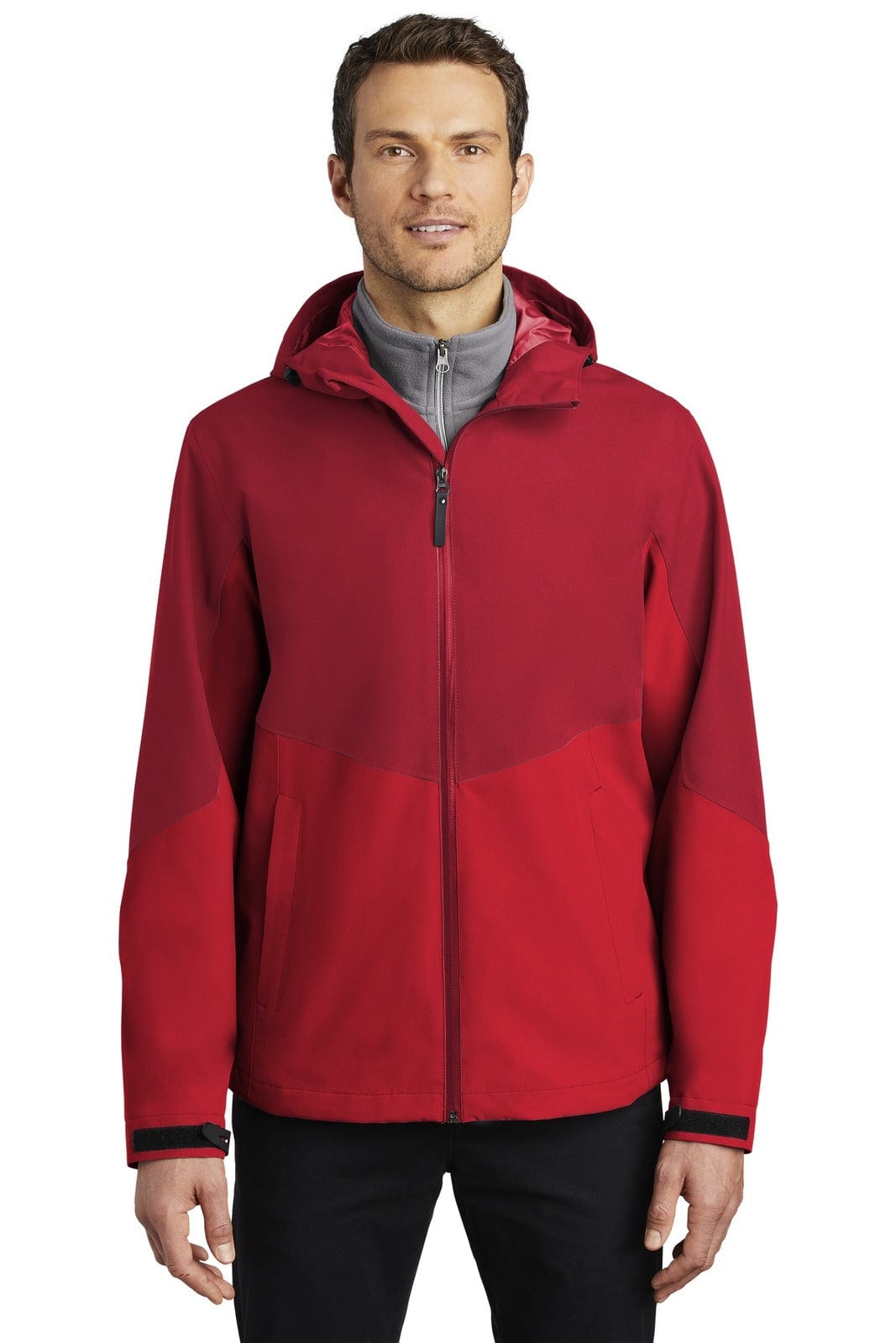 A man is wearing a red Port Authority Tech Rain Jacket with a hood, featuring a zipped front and a logo on the chest.