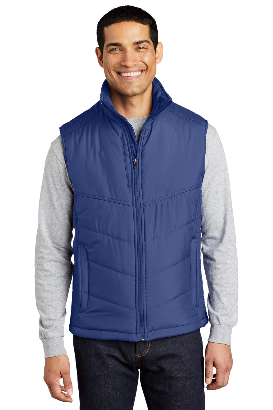 A man wearing a blue puffy vest over a grey long-sleeve shirt, with a logo on the vest.