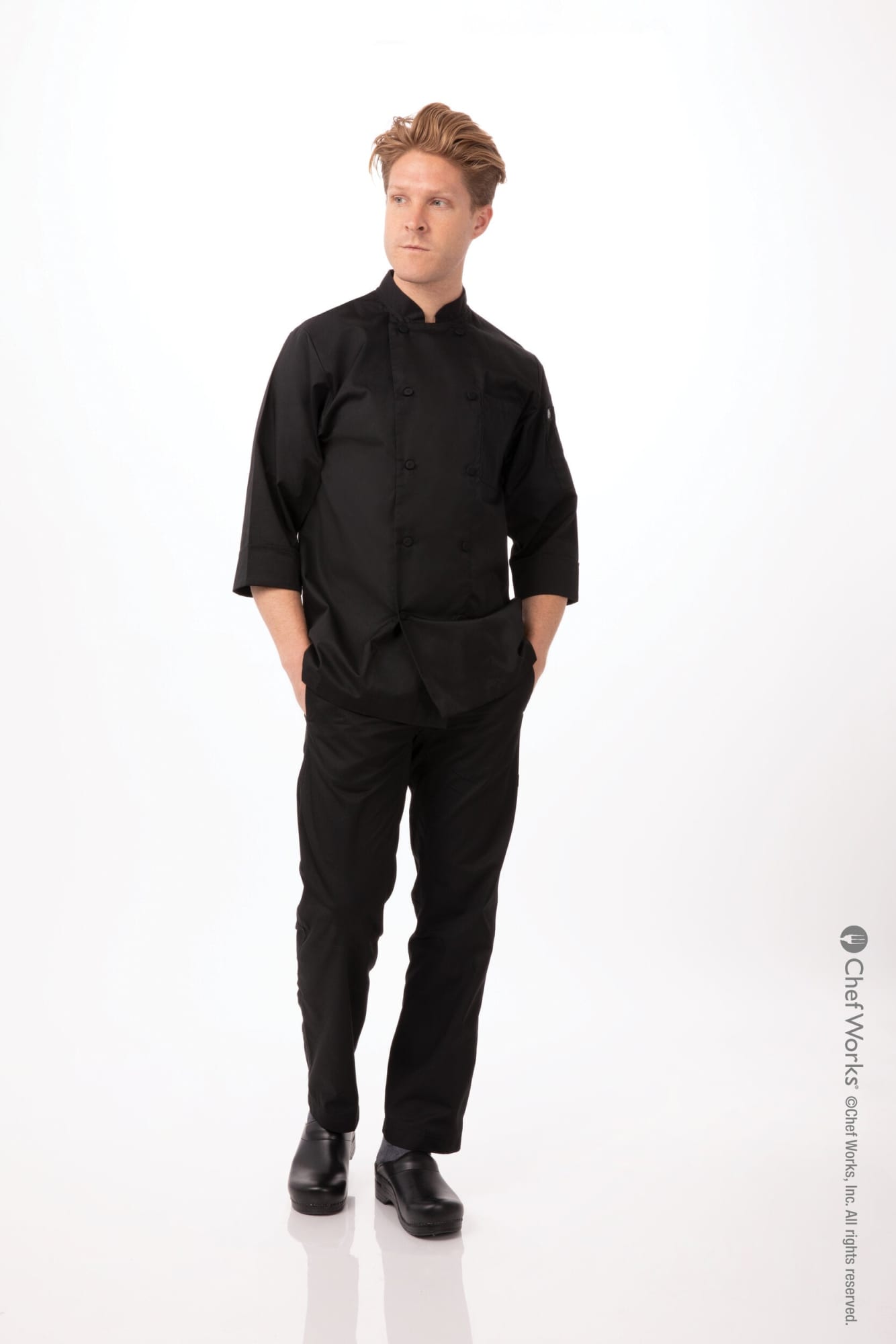A black men's chef jacket paired with matching pants, worn by a standing model. The image features a logo.