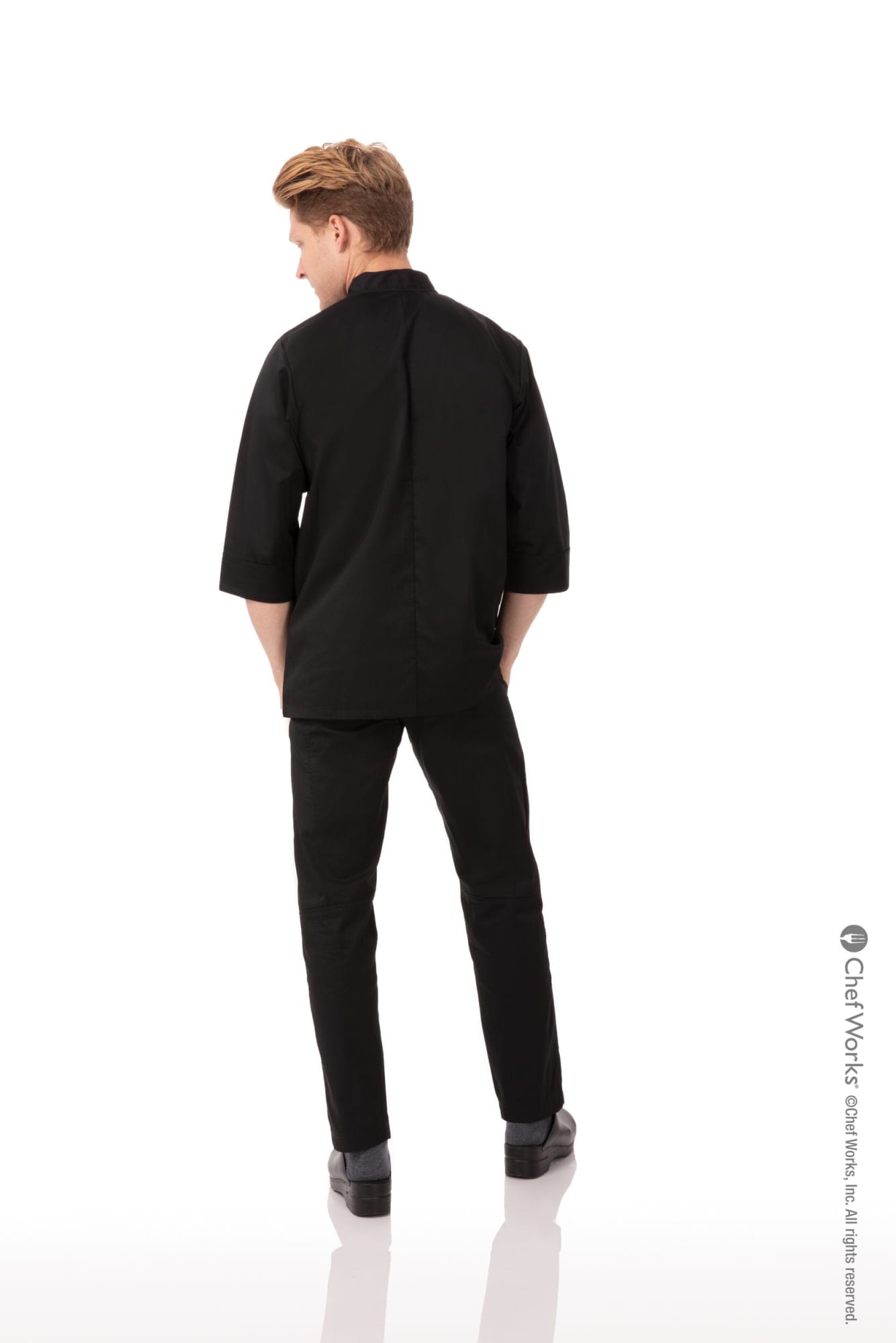 A black men's chef jacket is displayed, with a model positioned from the back, styled with matching black trousers.