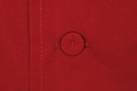 A red chef jacket featuring a round button detail, with a visible seam. It has a logo on the fabric.
