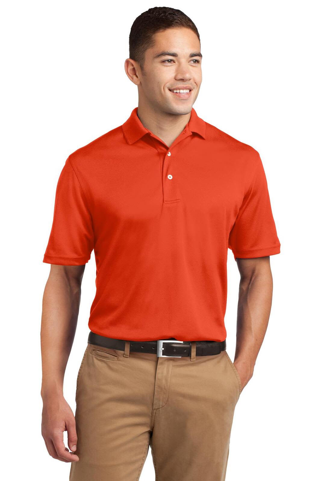 A man wearing an orange Sport-Tek Dri-Mesh Polo shirt, paired with light brown trousers, and smiling.