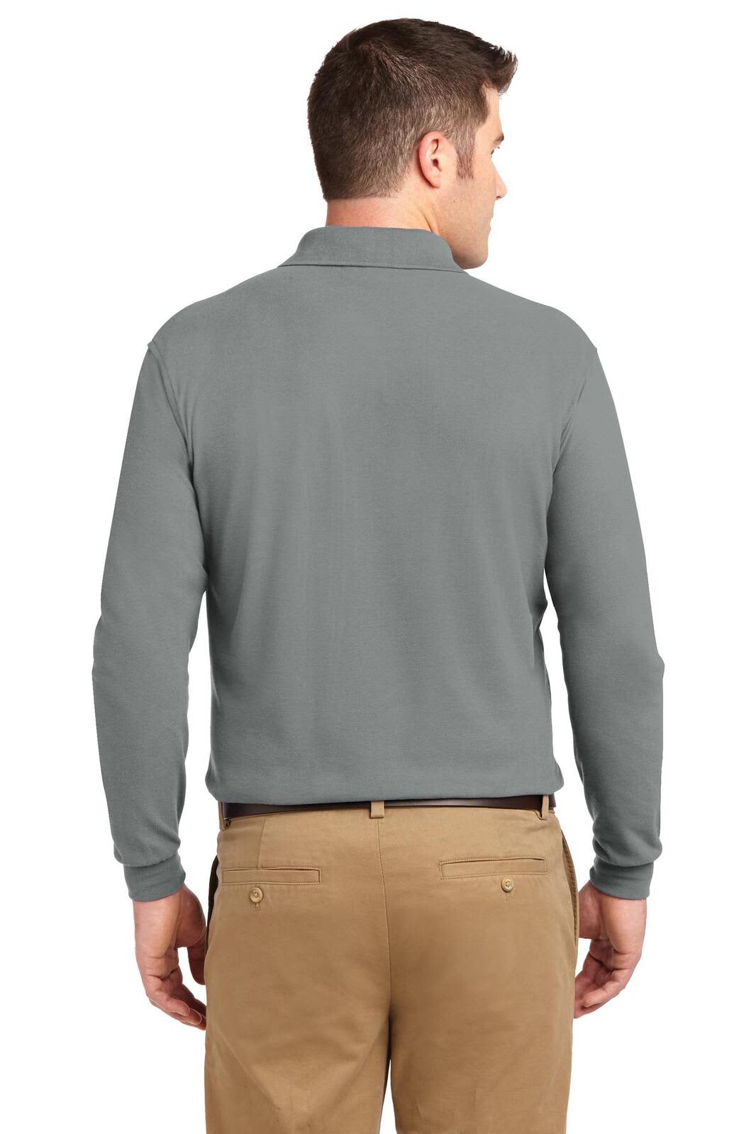 A man wears a grey long sleeve polo shirt from the back, paired with tan trousers. The shirt features a logo.