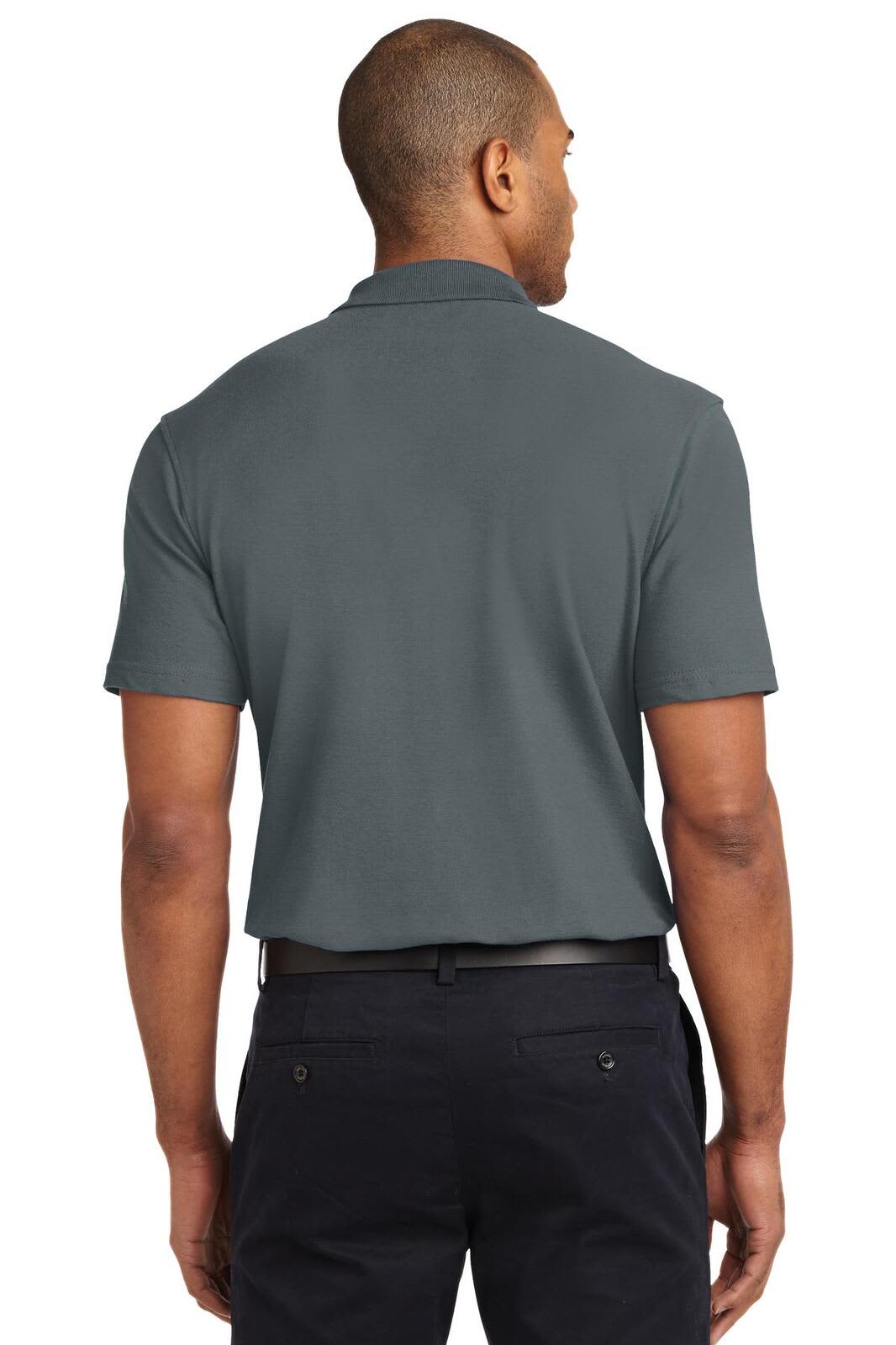 A man in a dark grey stain-resistant polo shirt viewed from the back, paired with dark trousers.