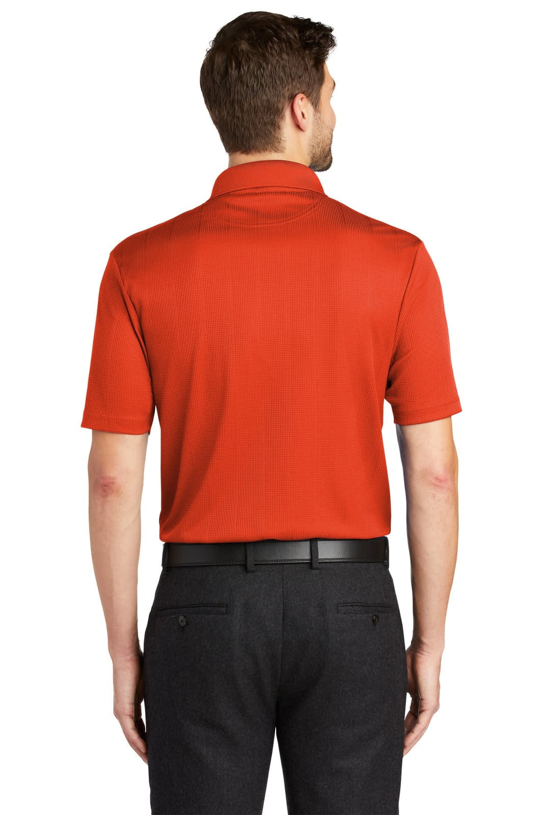 A back view of a man wearing an orange Port Authority Performance Fine Jacquard Polo with a black belt and dark trousers.