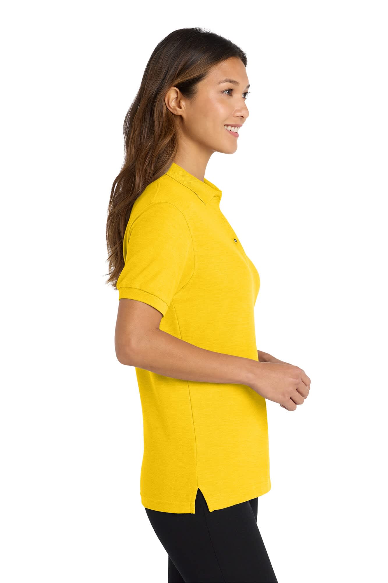 A woman stands in profile wearing a bright yellow polo shirt with a logo and side slits at the hem.