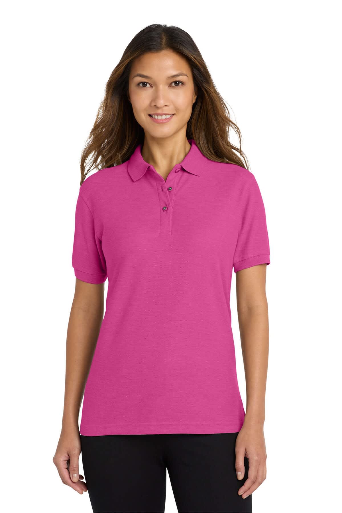 A pink polo shirt for women, featuring a collar and a logo. The model is wearing it with black pants.