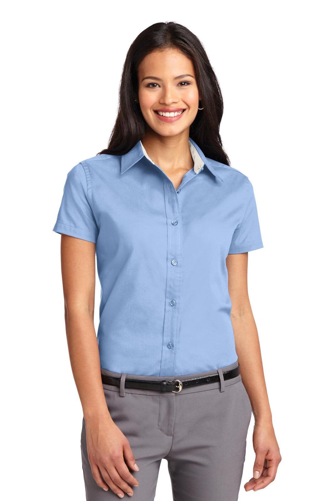 A short-sleeve, light blue button-up shirt with a collar, worn by a smiling woman. Includes a logo.