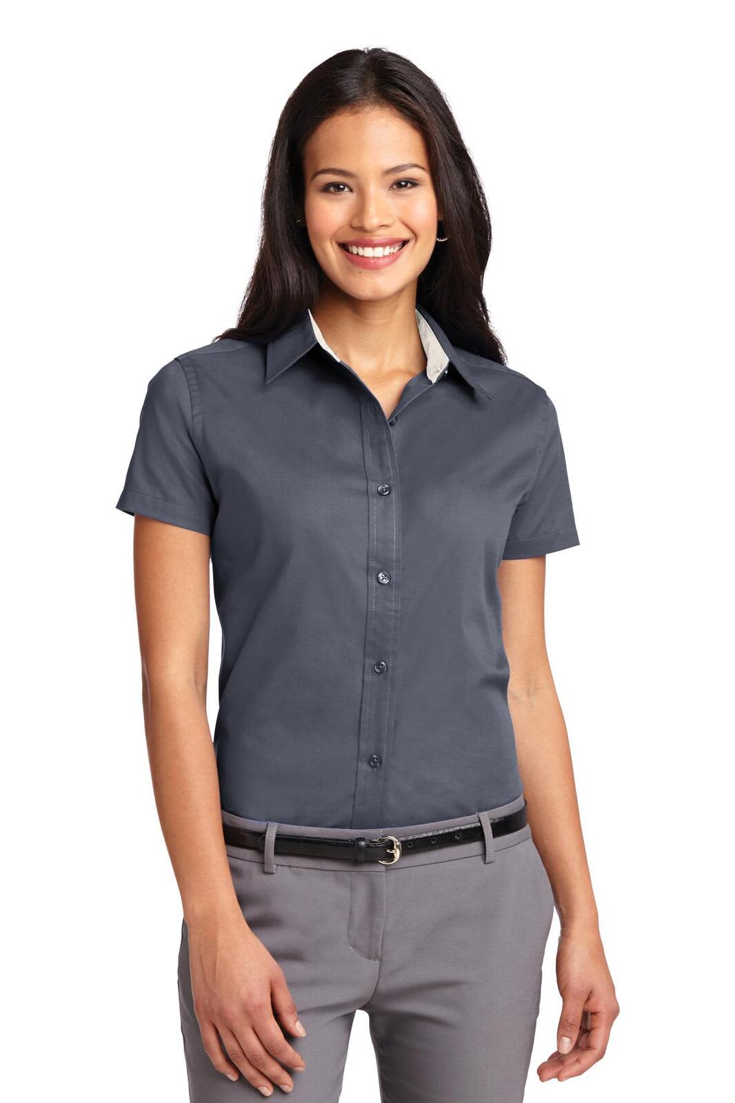 A lady wearing a navy short sleeve button-up shirt with a collar, featuring a logo on the chest.