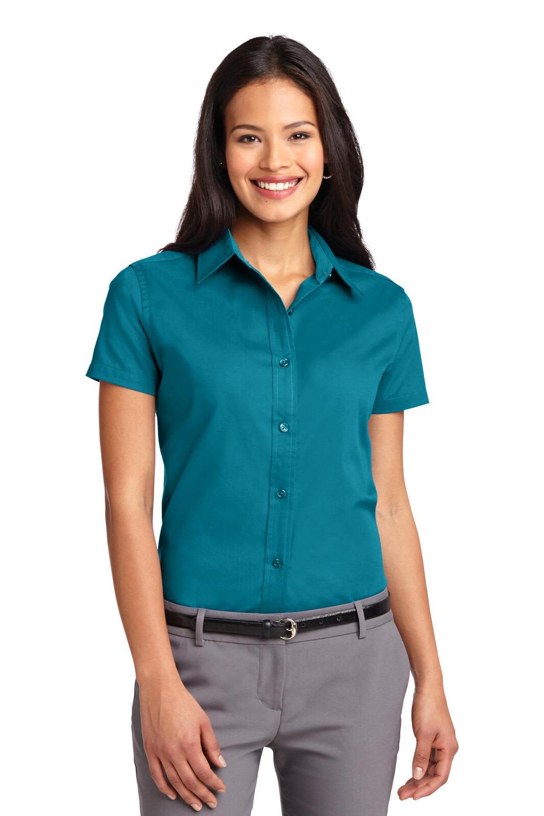 A woman models a teal short sleeve button-up shirt, featuring a collar and a logo on the chest.