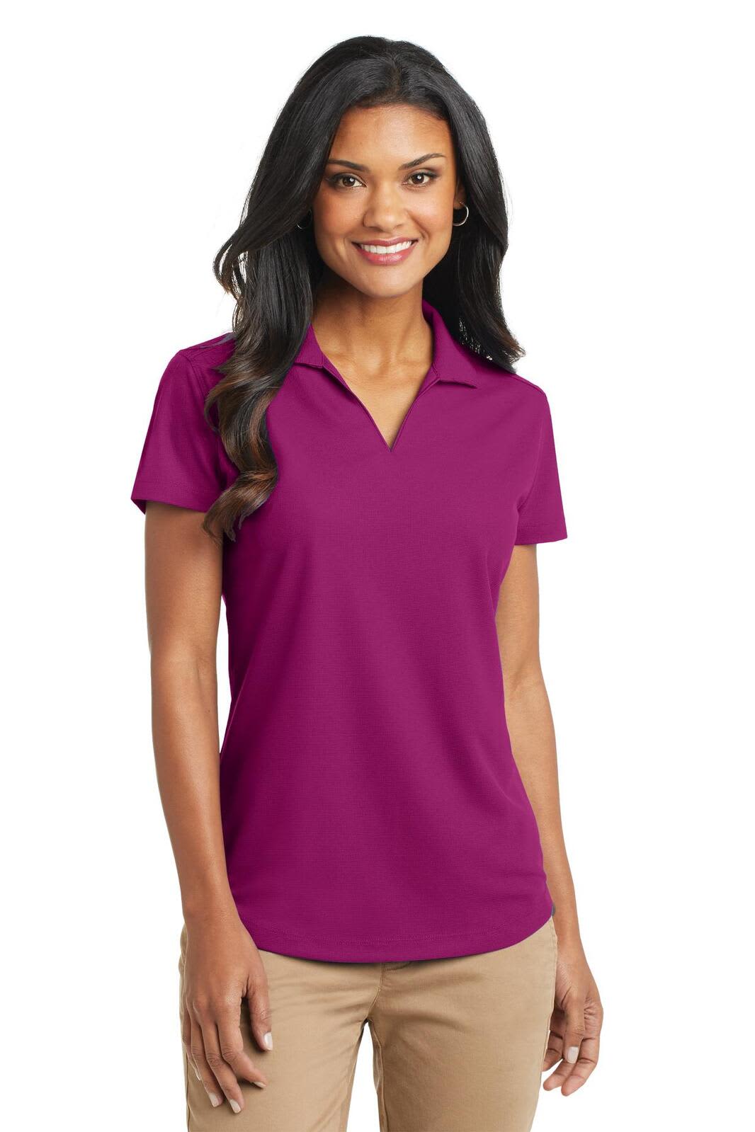 A woman wears a purple Port Authority Ladies Dry Zone Grid Polo shirt, featuring a collar and short sleeves.