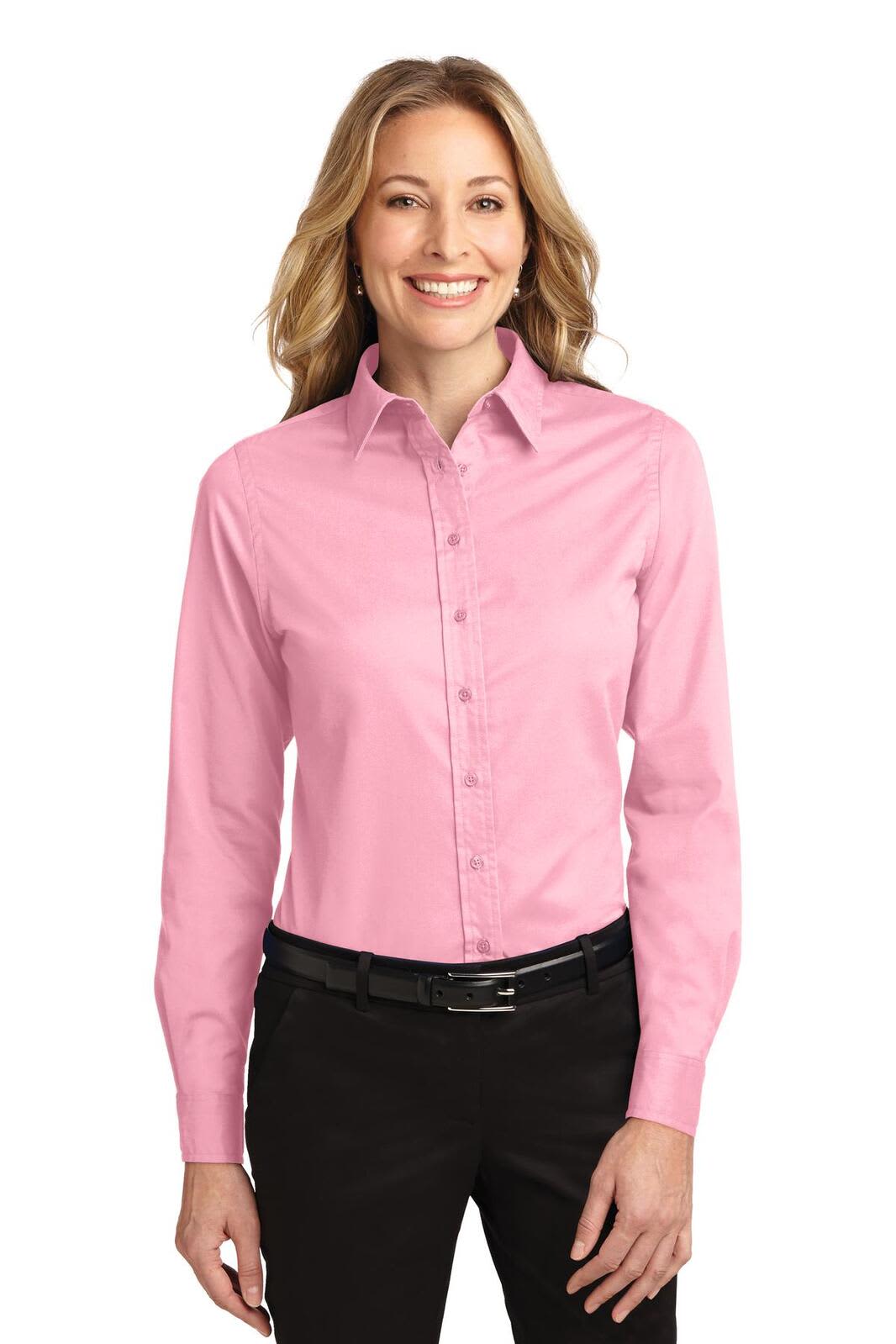 A light pink long sleeve button-up shirt with a collar, featuring a logo, worn by a smiling woman.