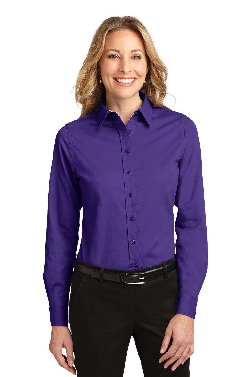 A woman wearing a purple long sleeve button-up shirt, featuring a collar and a sleek design. The shirt has a logo.