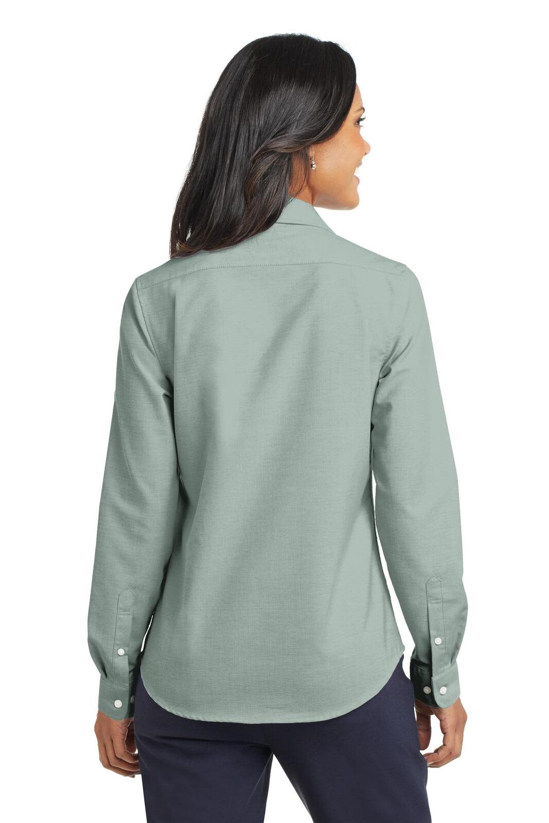 A woman is wearing a mint green button-up shirt, showcasing the back view and long sleeves. The shirt has a logo.