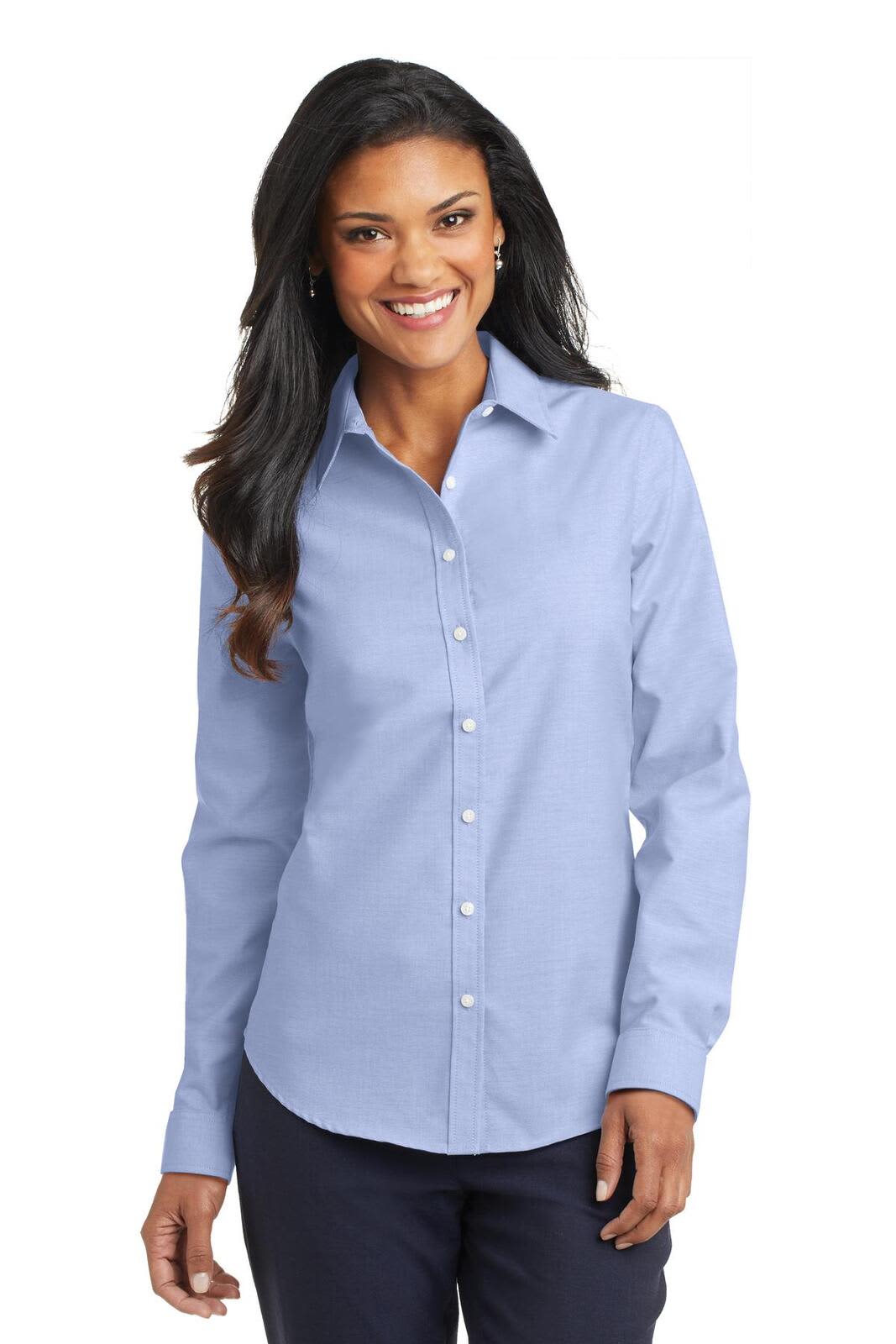 A woman wearing a light blue button-up shirt with long sleeves and a collar. The shirt has a logo on it.