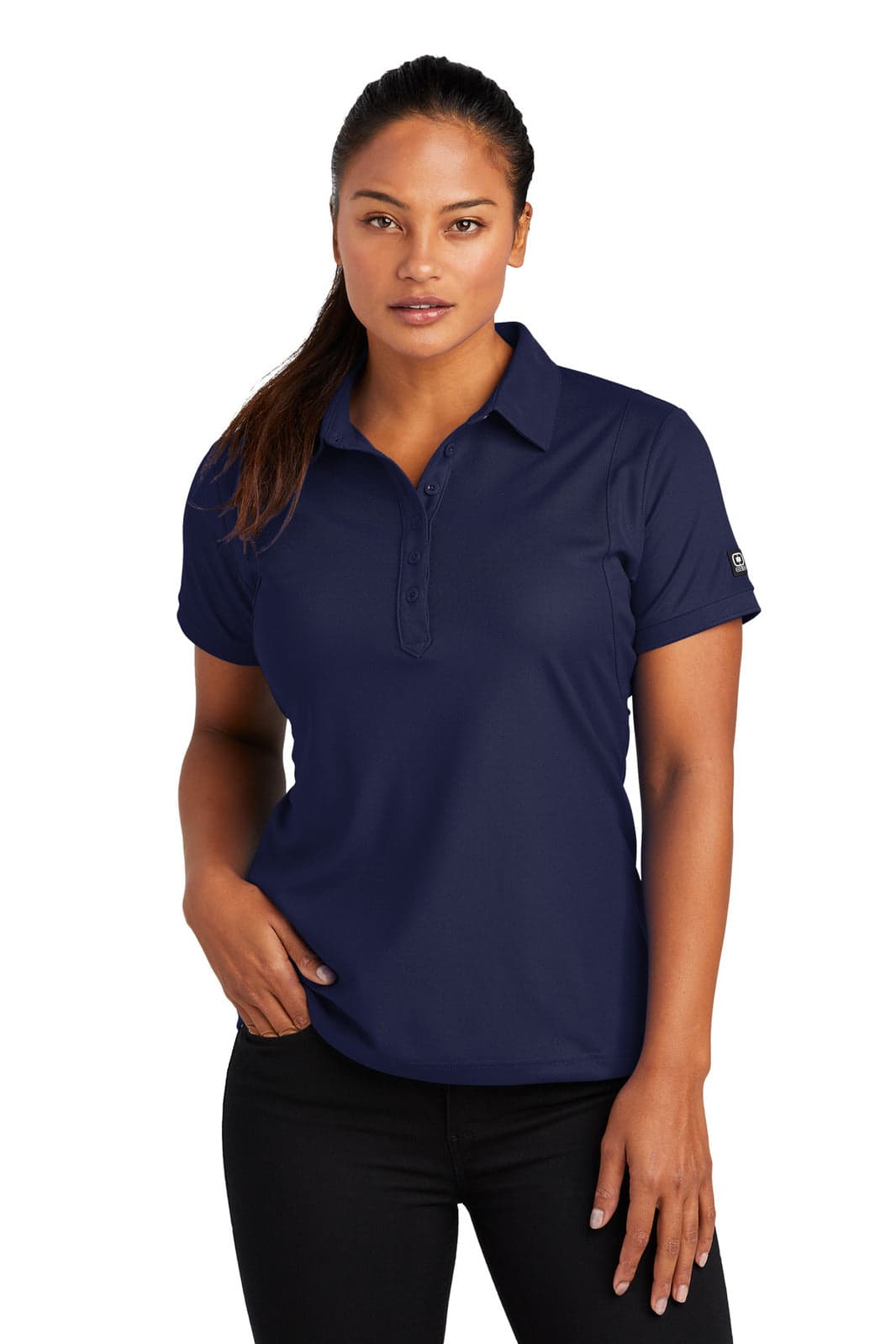 A woman wearing a navy blue polo shirt with a logo on the sleeve, styled with black pants.