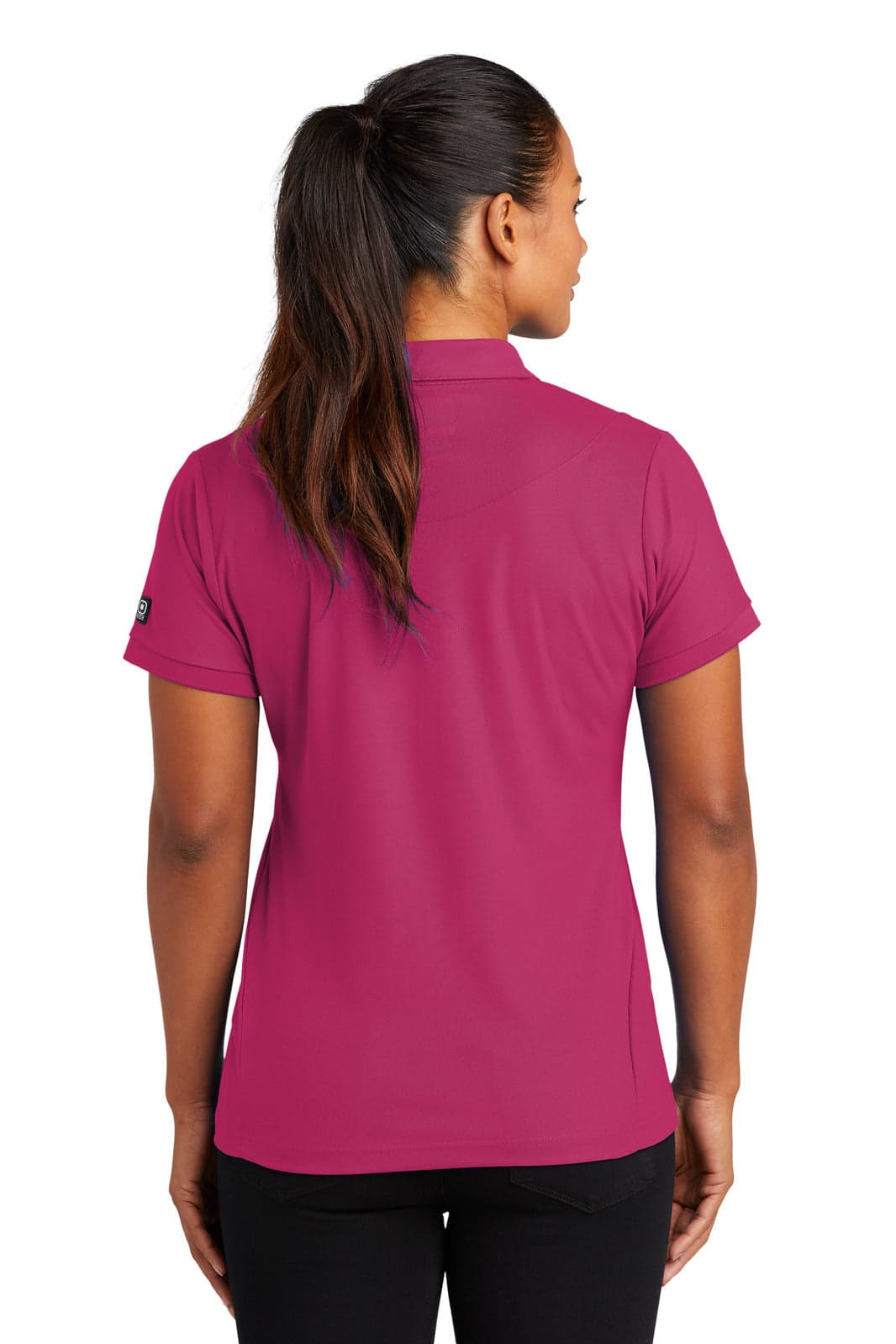 A pink polo shirt is displayed from the back, featuring a short sleeve design and a logo on the sleeve.