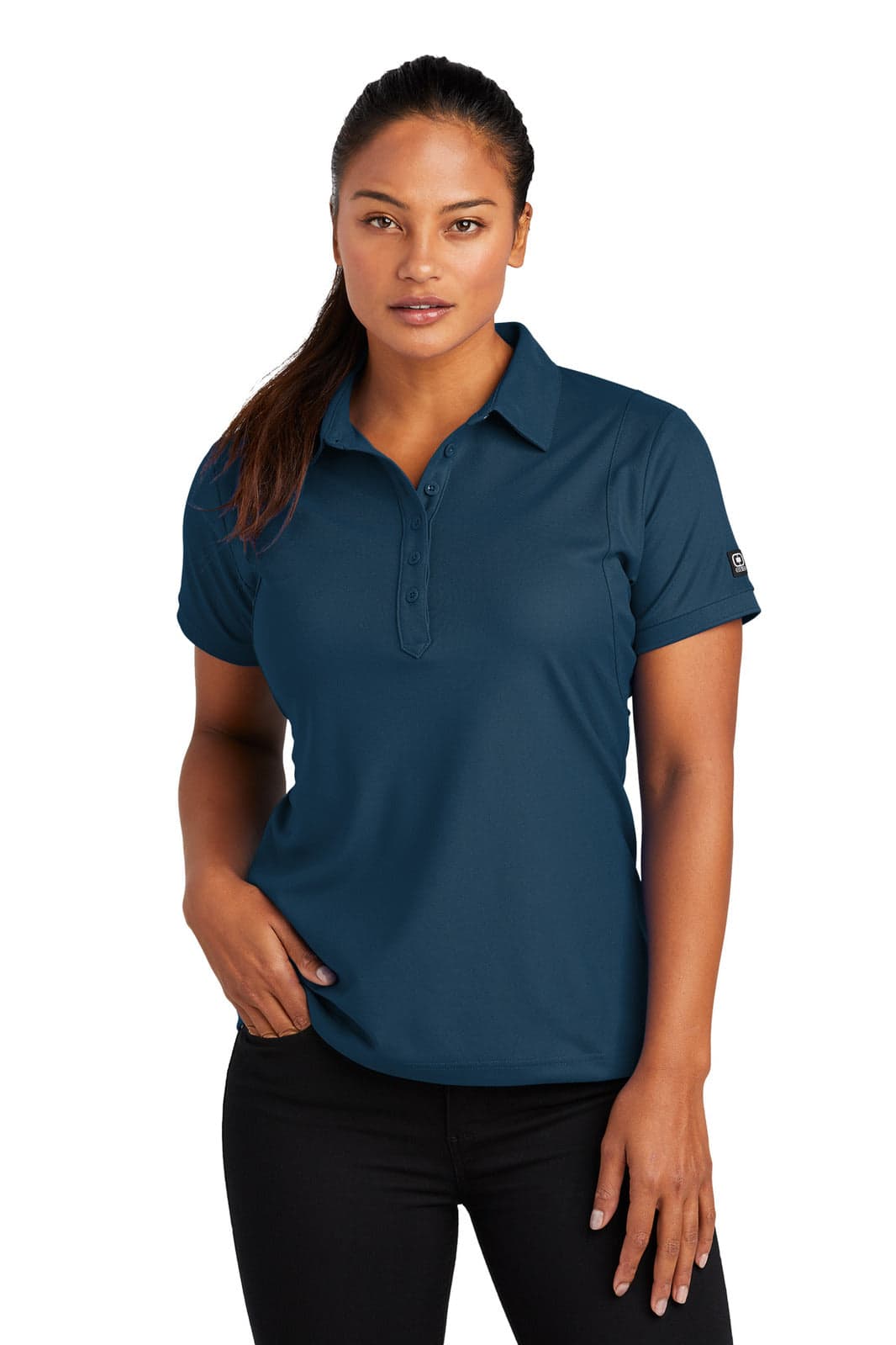 A woman models a navy blue polo shirt with a logo on the sleeve, featuring a classic collar and short sleeves.