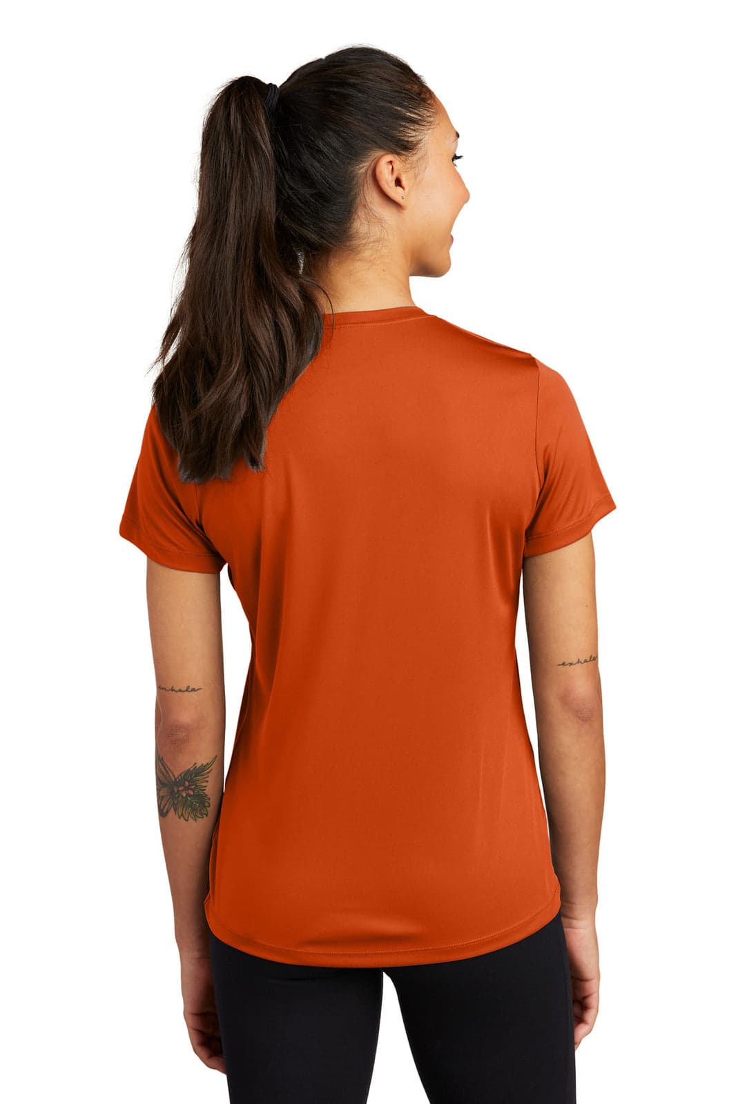 A woman wearing an orange Sport-Tek Ladies PosiCharge Competitor Tee, viewed from the back. The shirt features a logo.