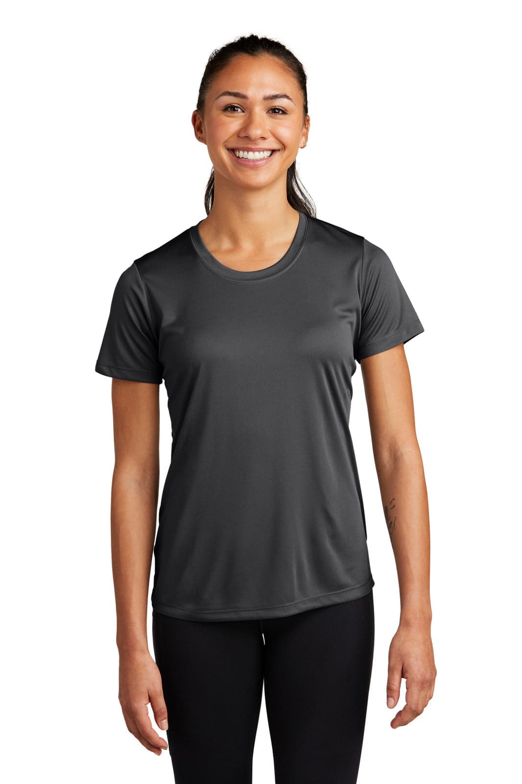 A woman wearing a dark grey athletic t-shirt with a crew neck and short sleeves. The shirt has a logo.