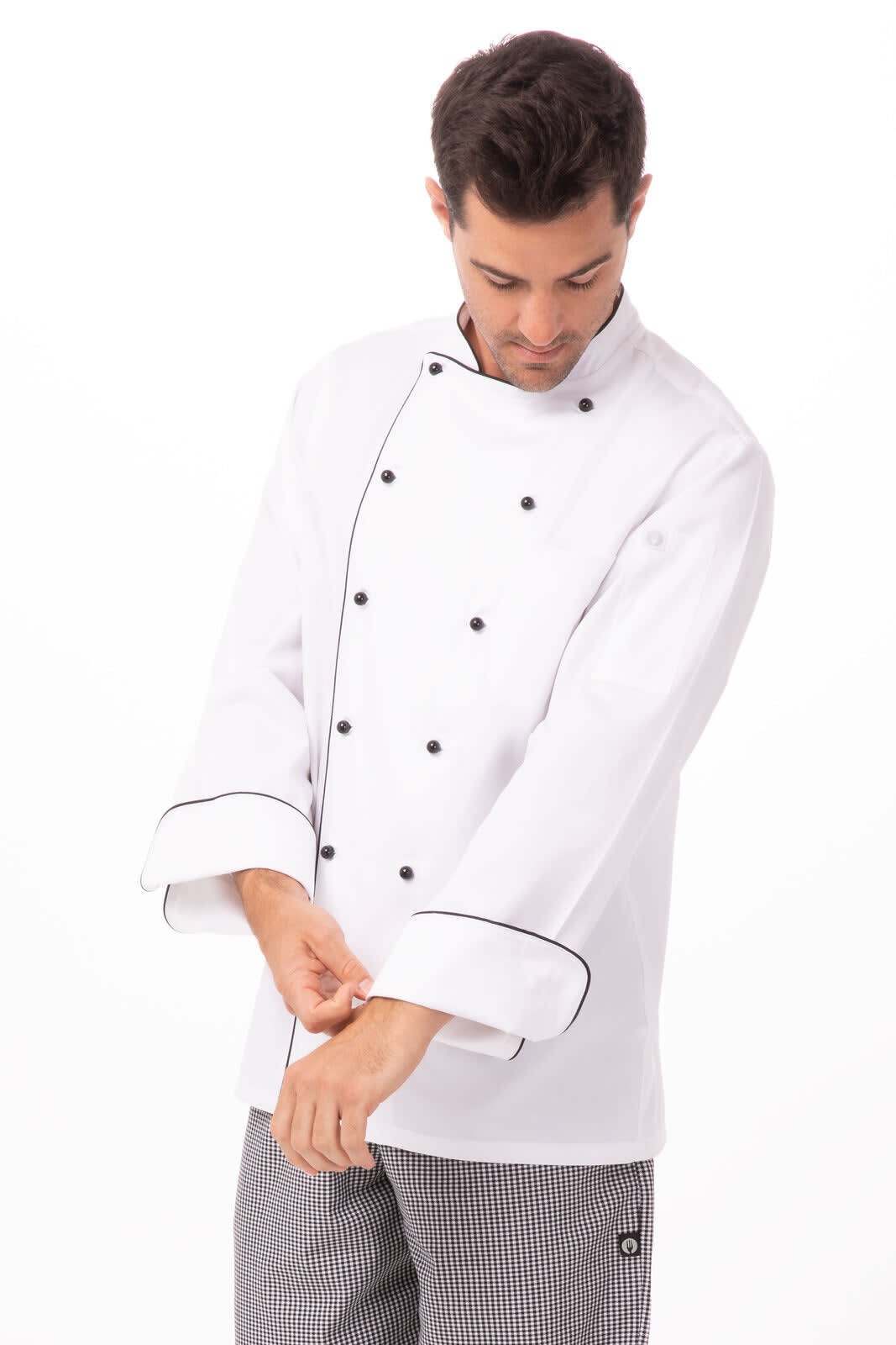 A white chef jacket with black piping and buttons, worn by a man adjusting his sleeves.