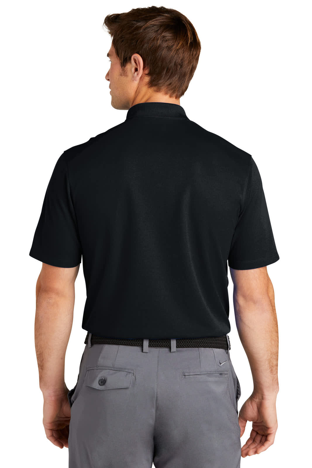 A back view of a man wearing a black Nike Dri-FIT Micro Pique 2.0 Polo shirt paired with grey trousers.
