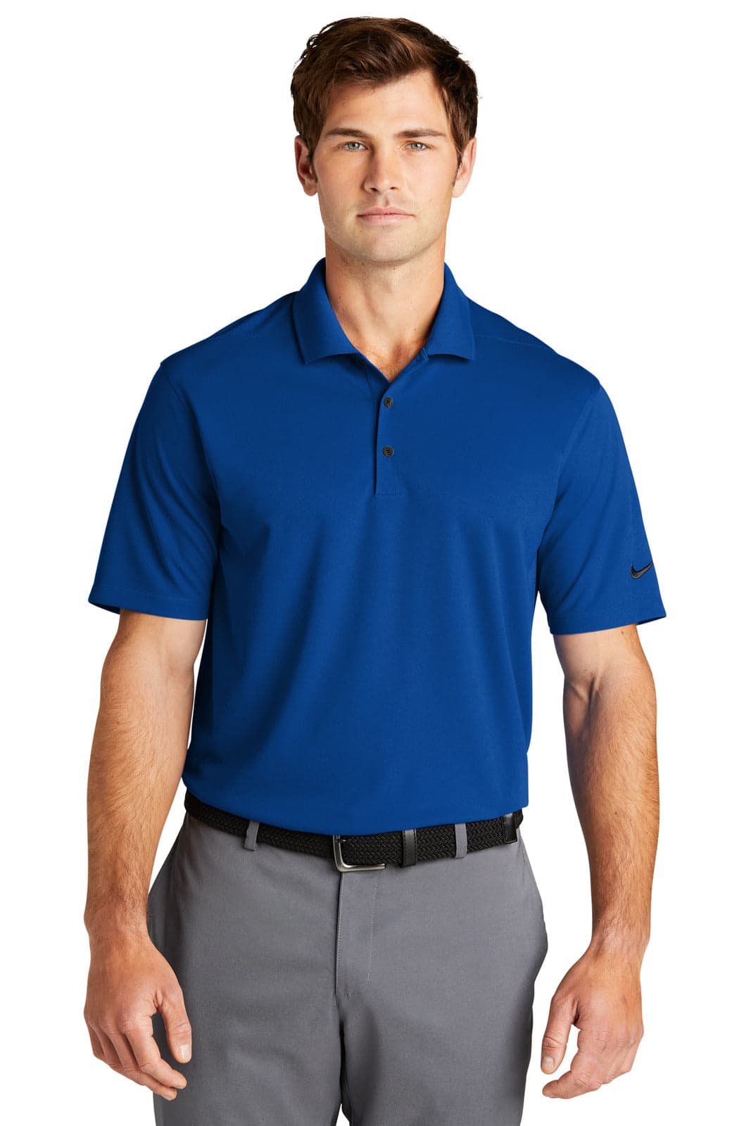 A man wearing a blue Nike Dri-FIT polo shirt stands confidently, paired with grey trousers. The shirt features a logo on the sleeve.