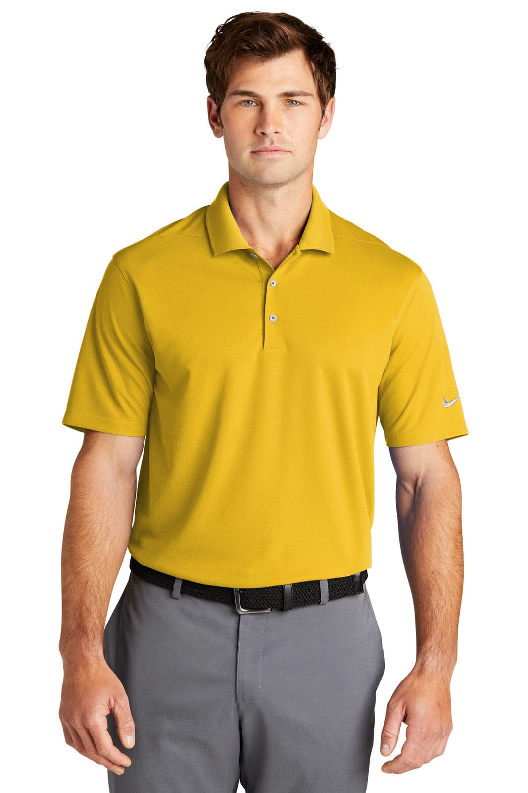 A man wearing a yellow polo shirt with a logo, styled with grey trousers and a belt.