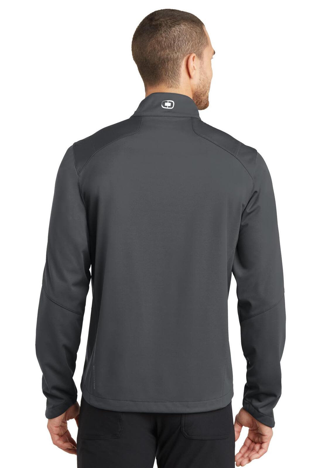 A man wearing a grey OGIO ENDURANCE Crux Soft Shell jacket, viewed from the back. The jacket has a logo on the collar.