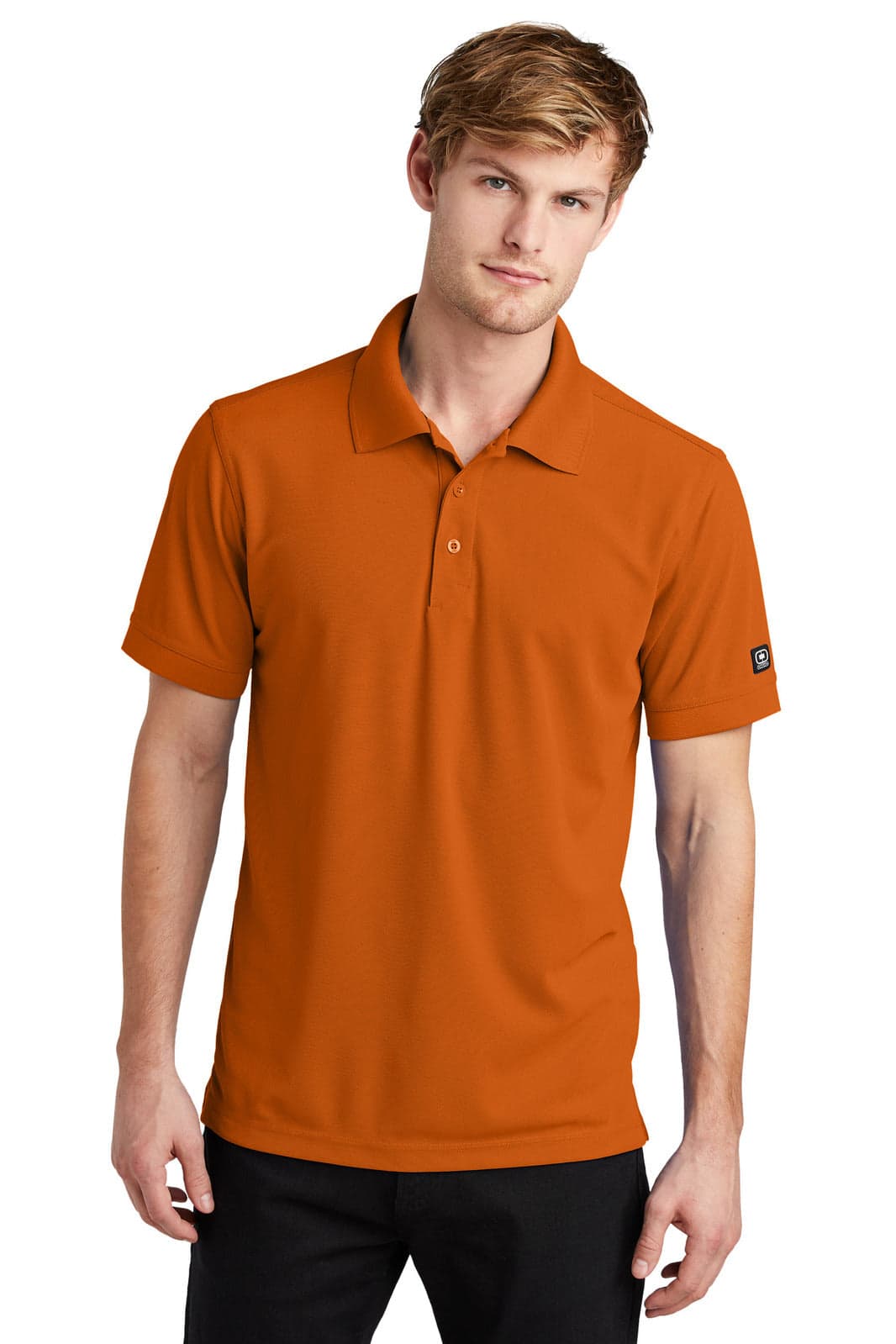 A man wearing an orange OGIO Caliber 2.0 polo shirt, featuring a small logo on the sleeve.