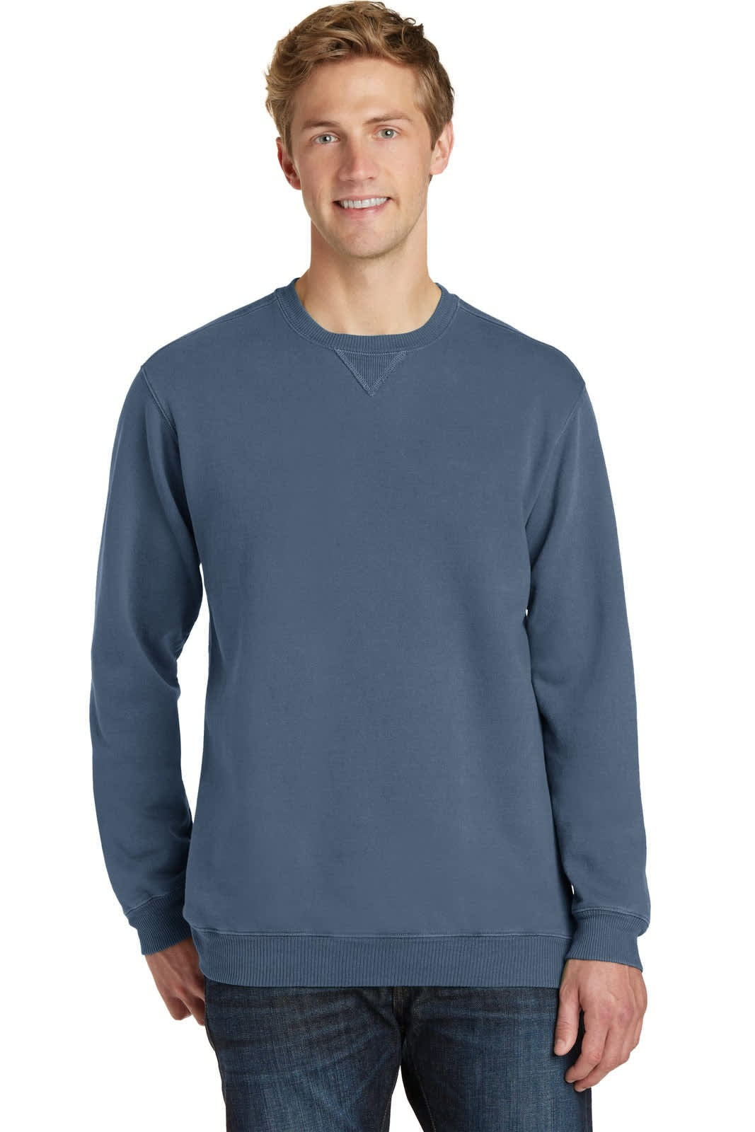 A man wearing a blue pigment-dyed crewneck sweatshirt, with a logo on the garment. Casual style with long sleeves.
