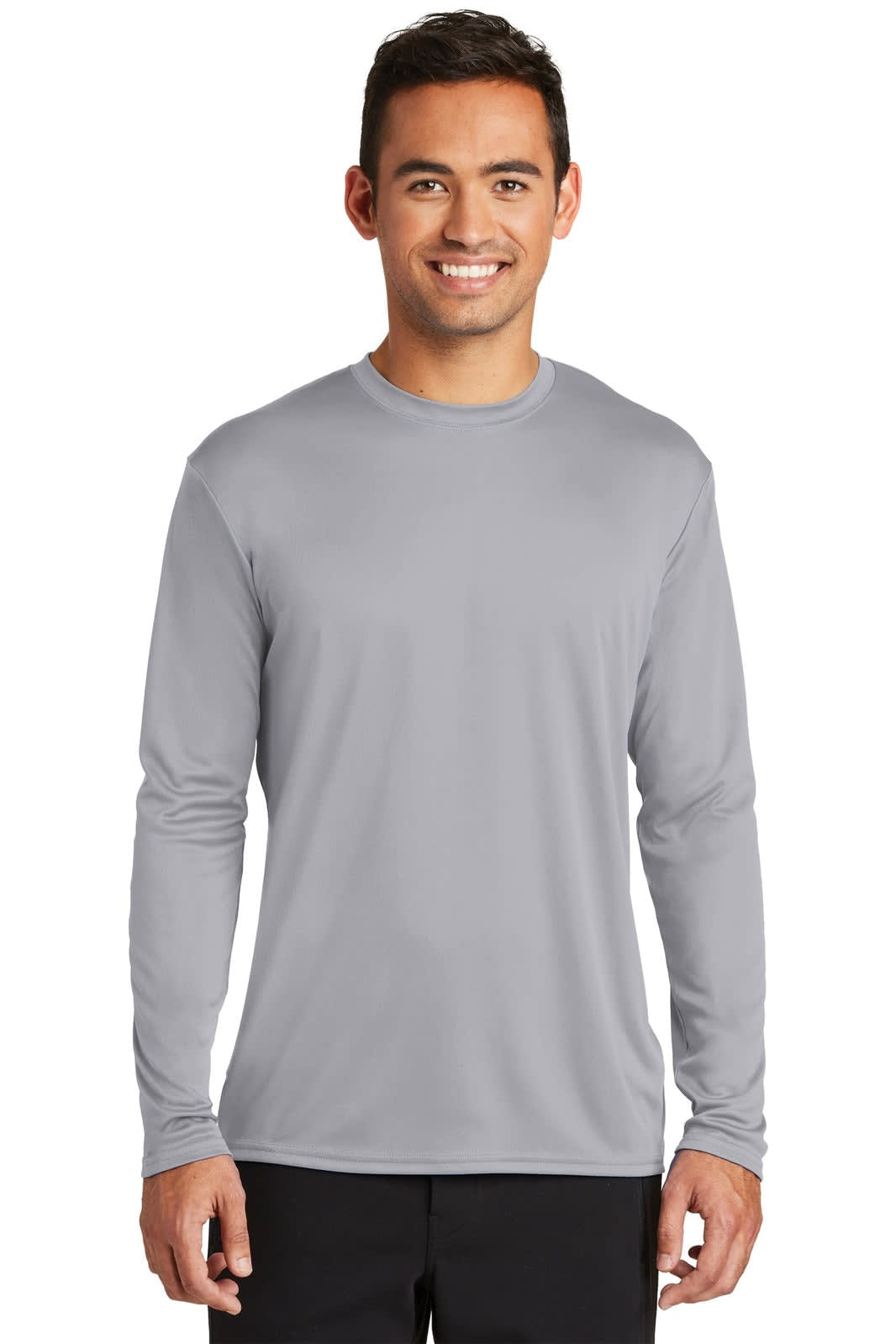 A long sleeve performance tee in grey, featuring a logo, modelled by a smiling man.